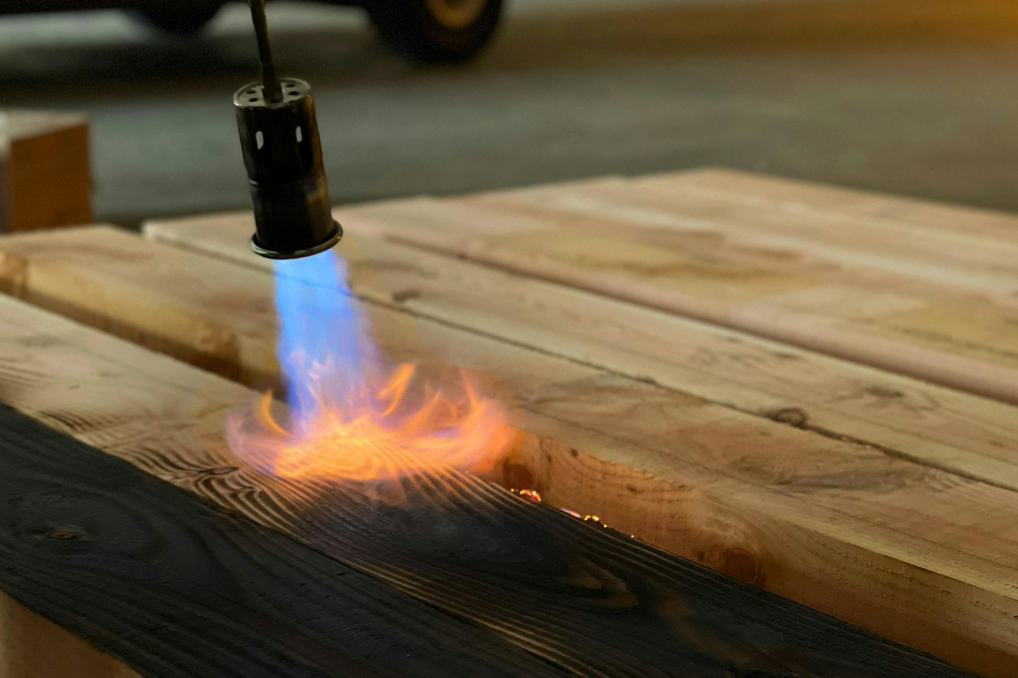 A length of timber being burnt or charred with a blow torch
