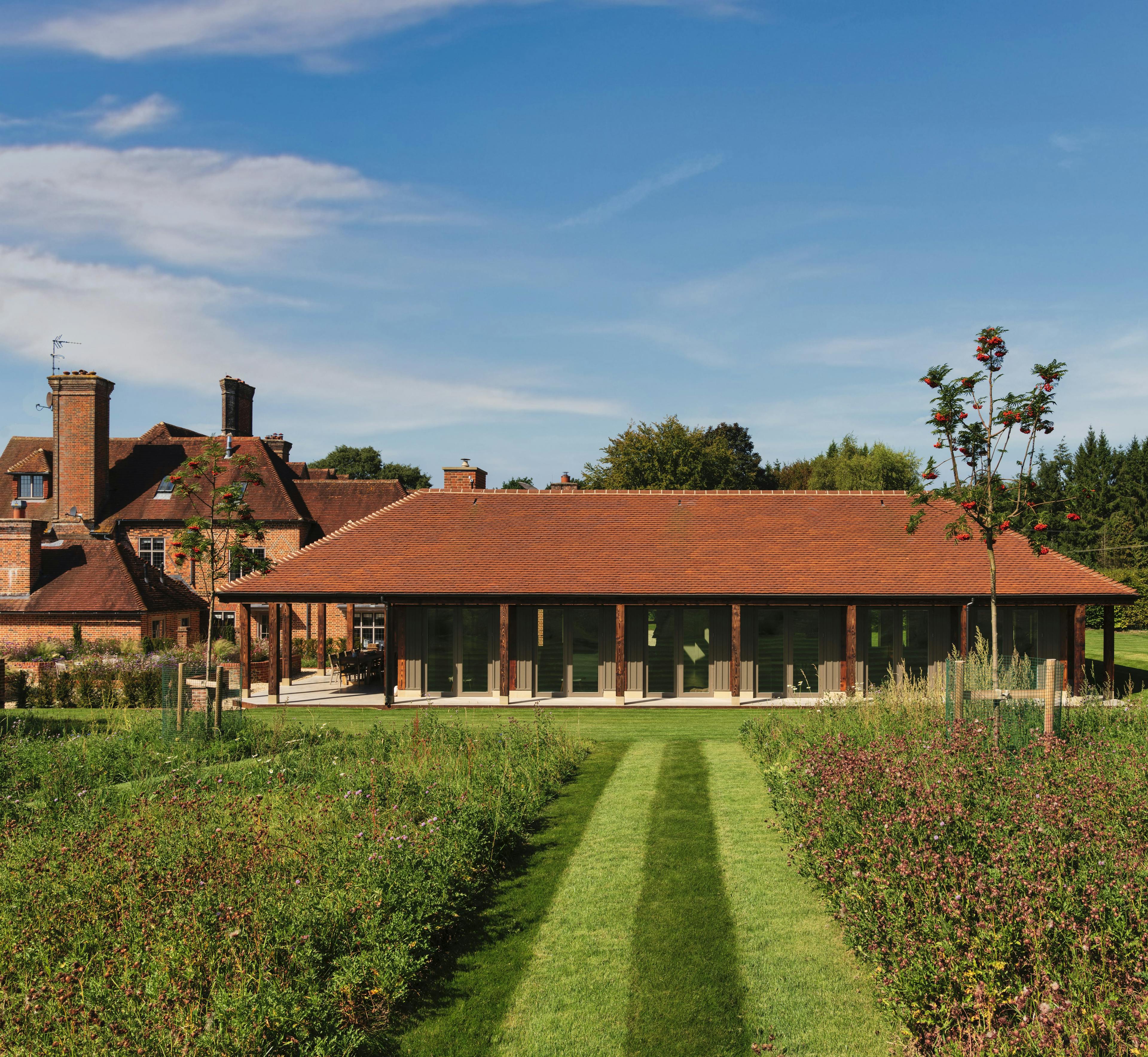A charred timber pavilion building in a large garden