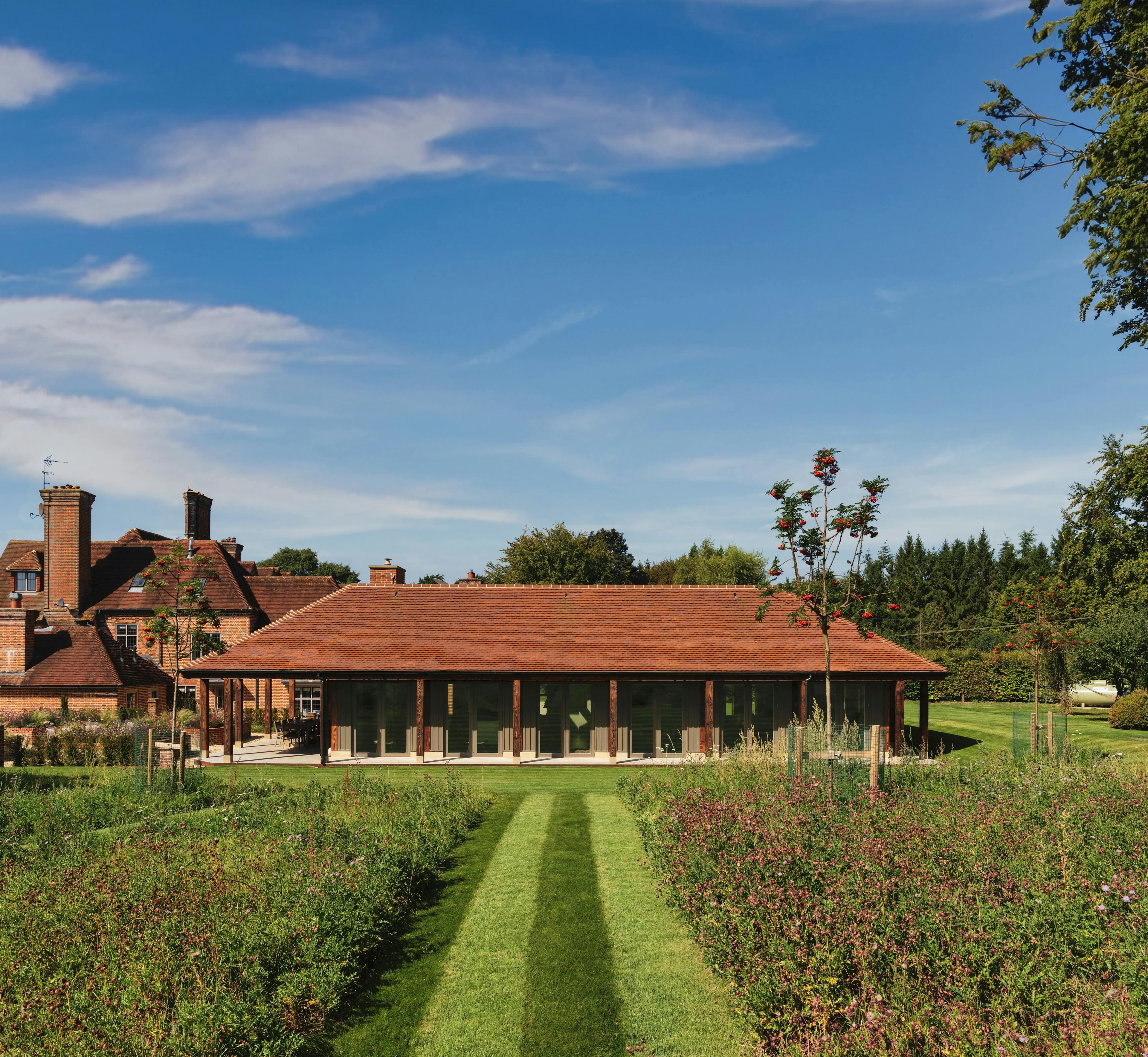 A charred timber pavilion building in a large garden