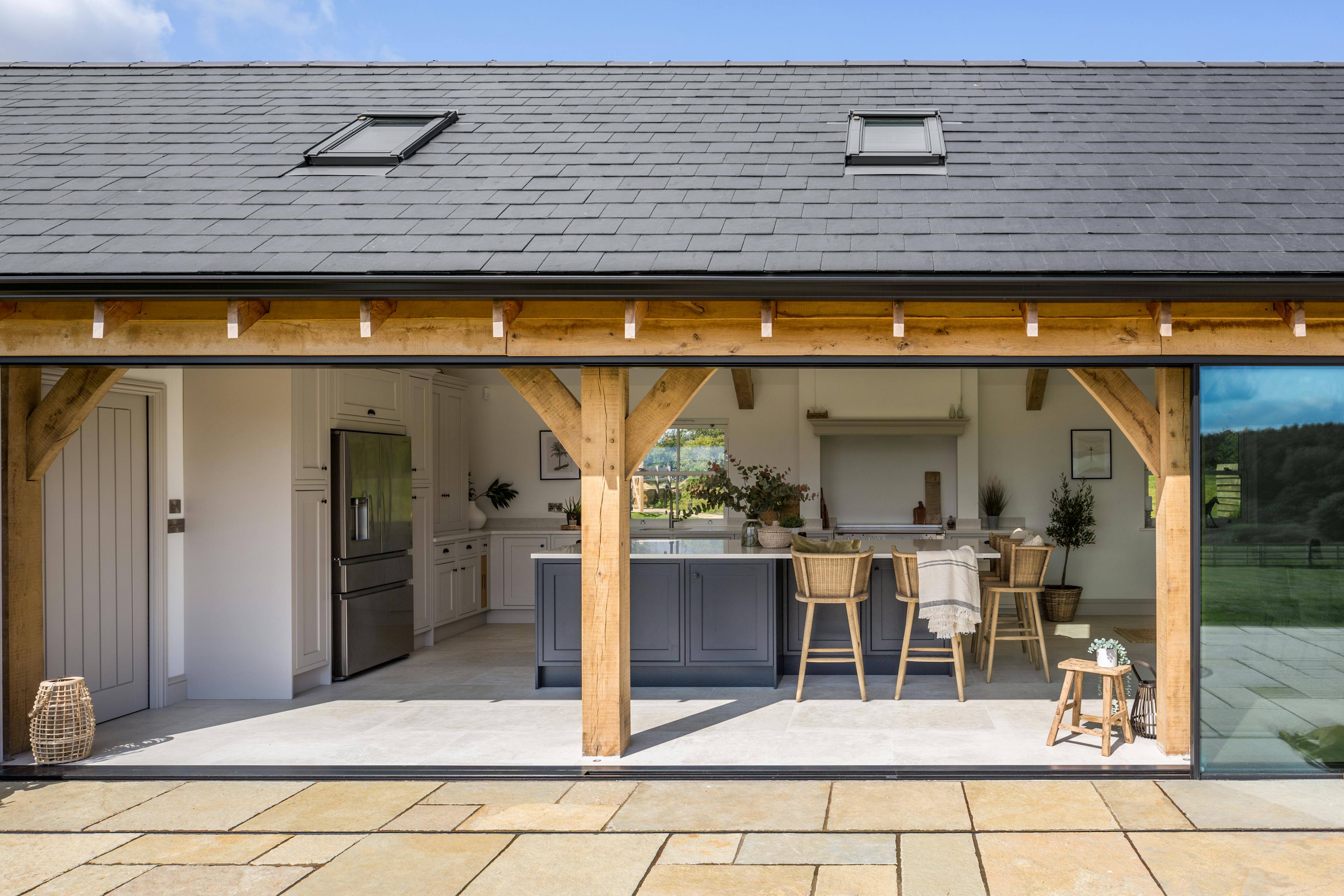 External view of an oak-framed open-plan kitchen featuring large glass joinery screens and bifold doors