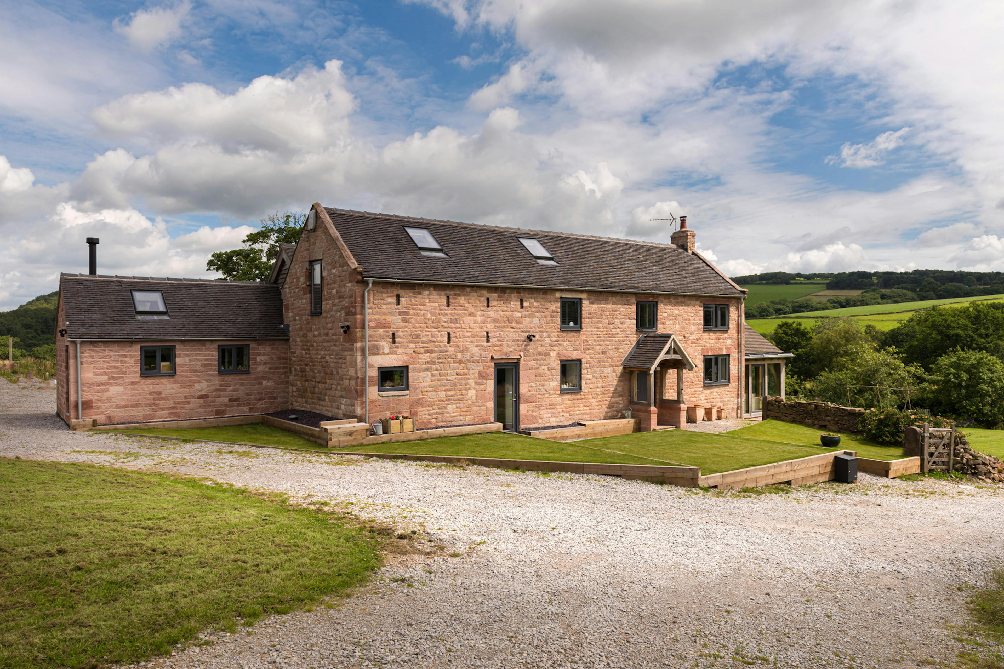 Exterior view of a two-story home featuring an oak-framed extensions that overlooks the countryside