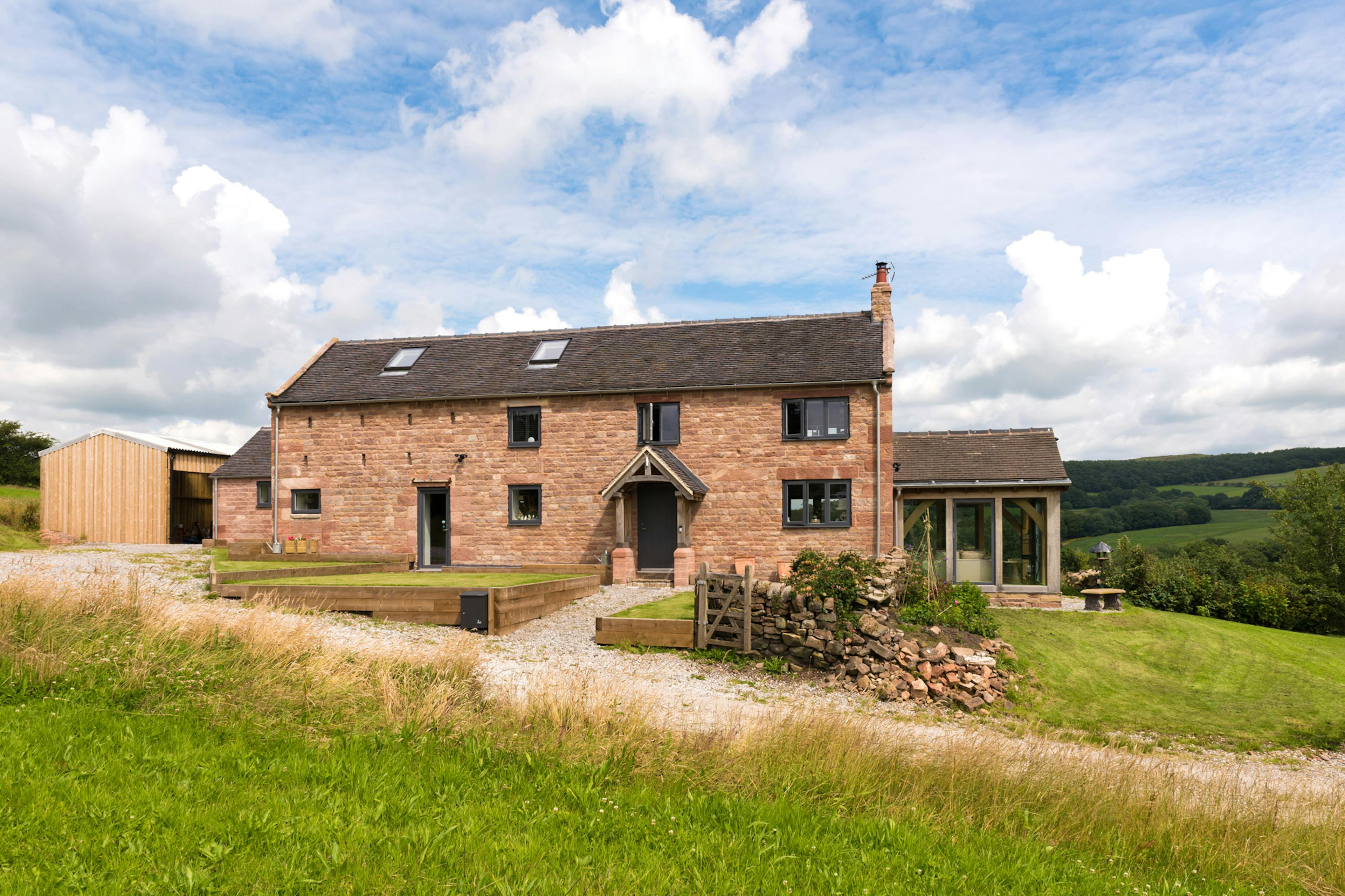 Exterior view of a farmhouse-style, two-story home featuring an oak-framed atrium