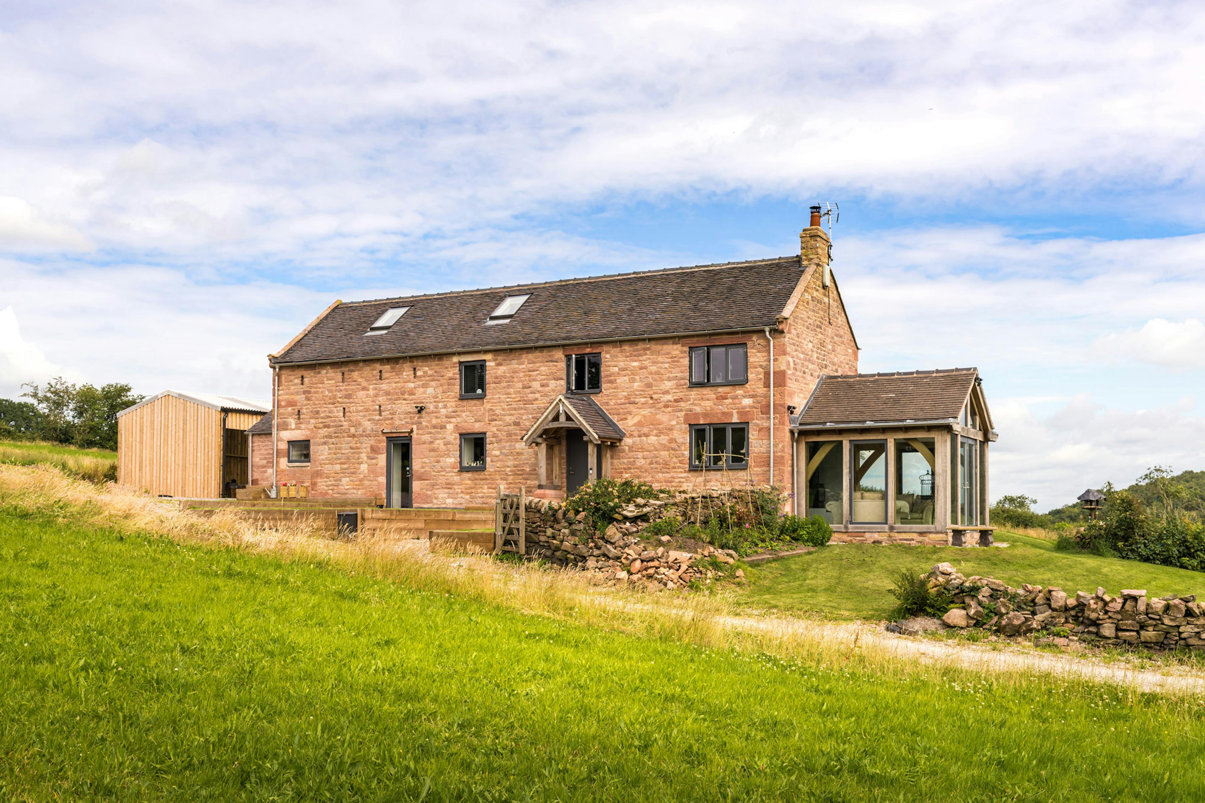 Exterior view of a reconstructed farmhouse featuring an oak-framed atrium that serves as a light-filled, galleried circulation hub