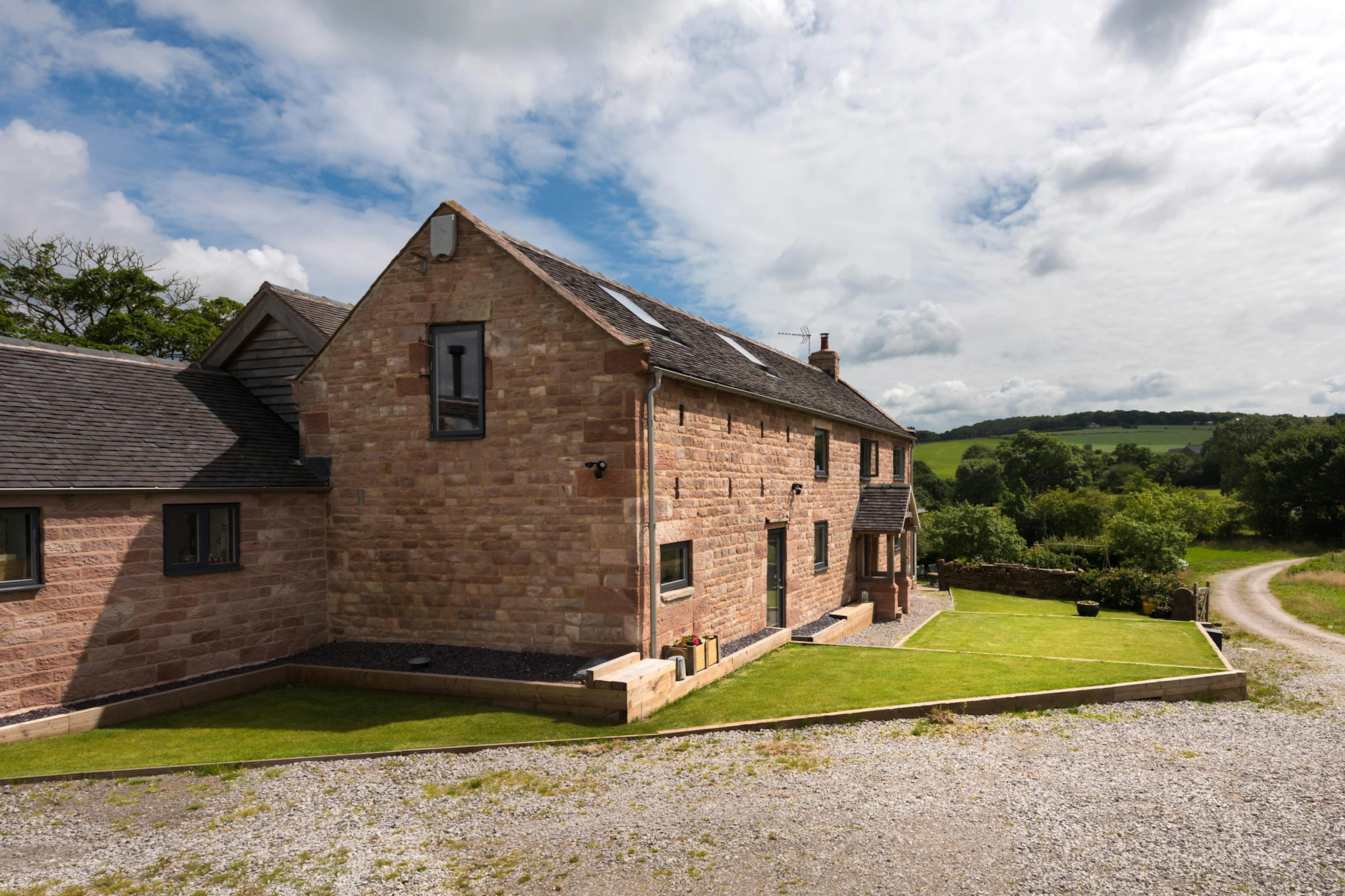 Exterior view of a two-story farmhouse with a scenic countryside backdrop