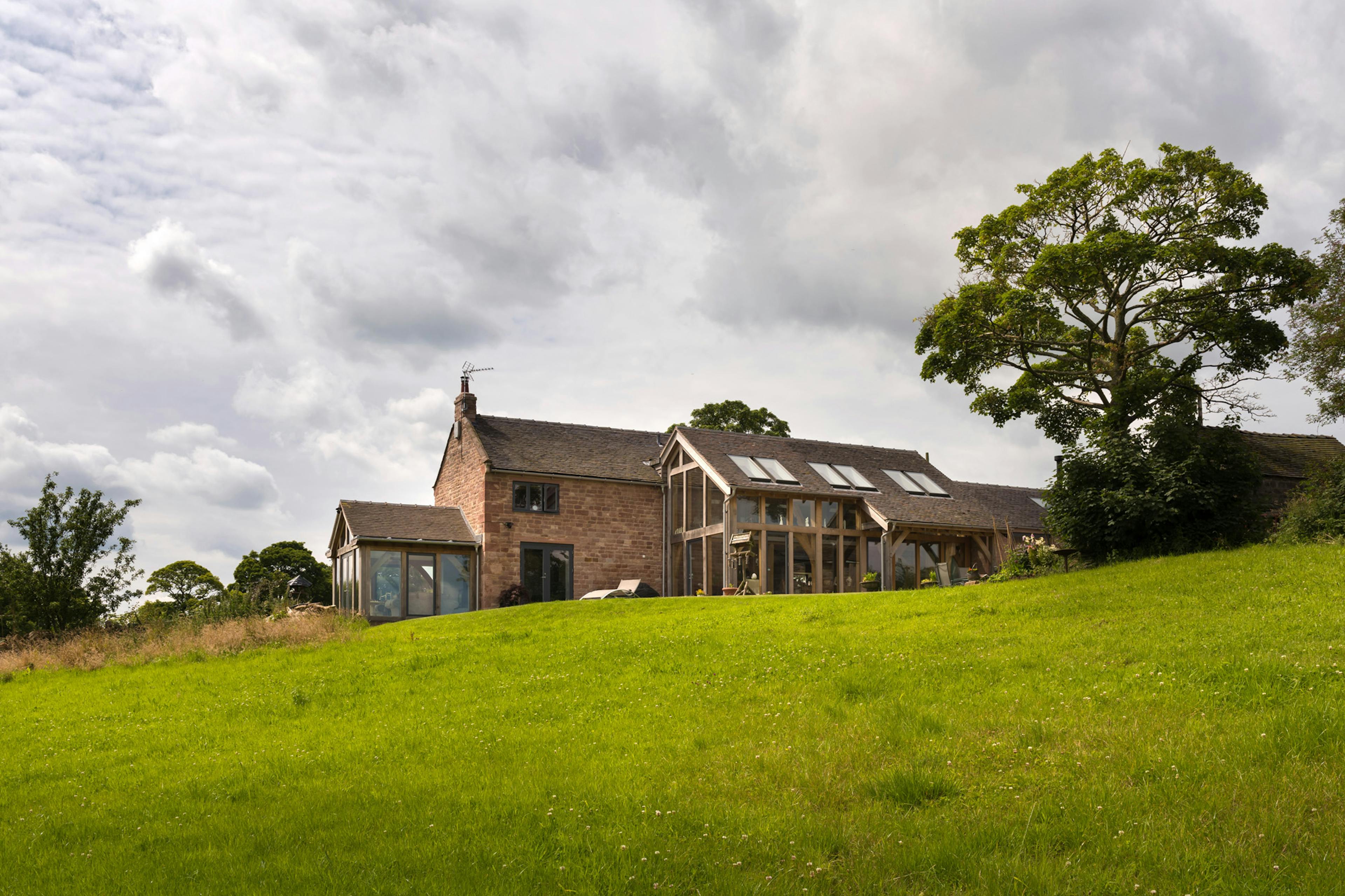 Exterior view of a farmhouse-style, two-story home with a lean-to and a two-story oak-framed extension