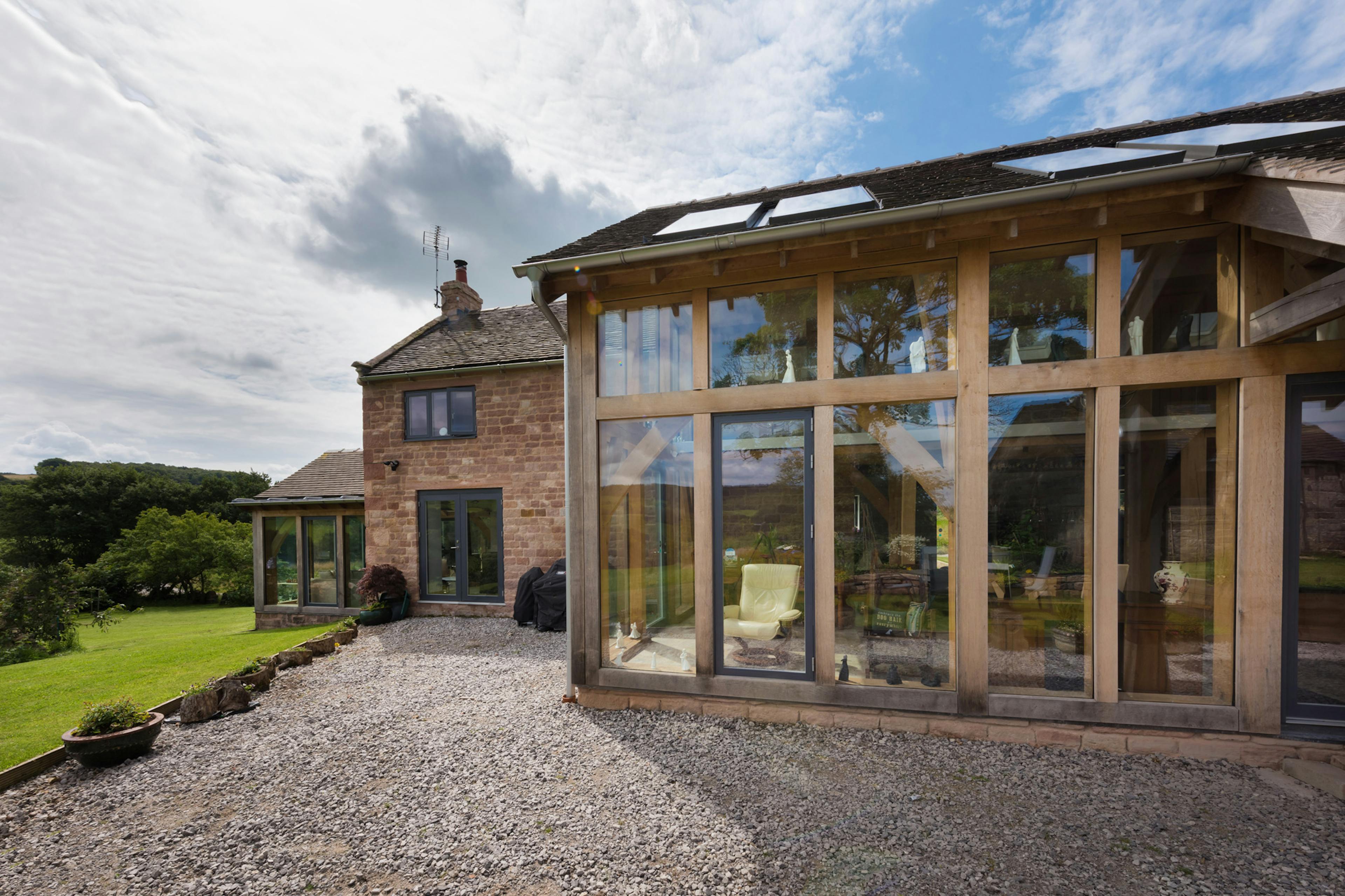Exterior view of a newly renovated farmhouse featuring a two-story oak-framed extension