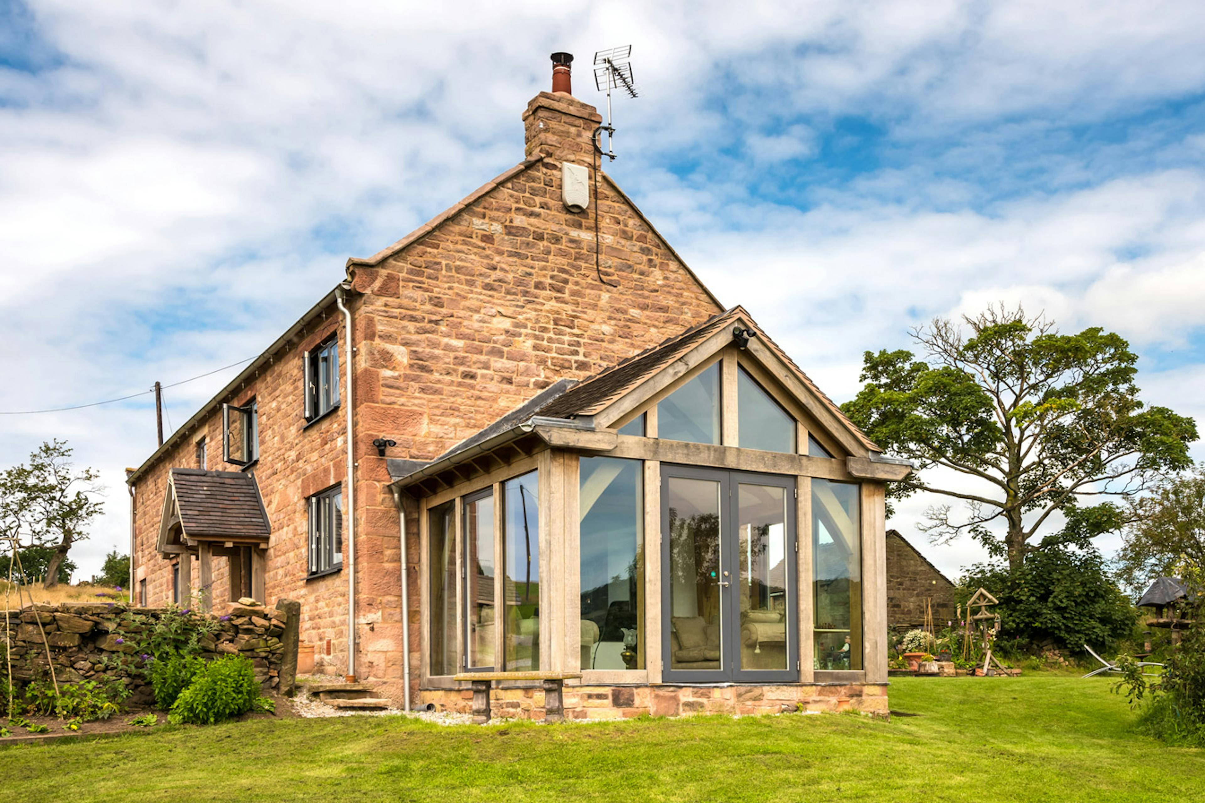 Exterior view of a two-story farmhouse with a direct-glazed oak-framed atrium.