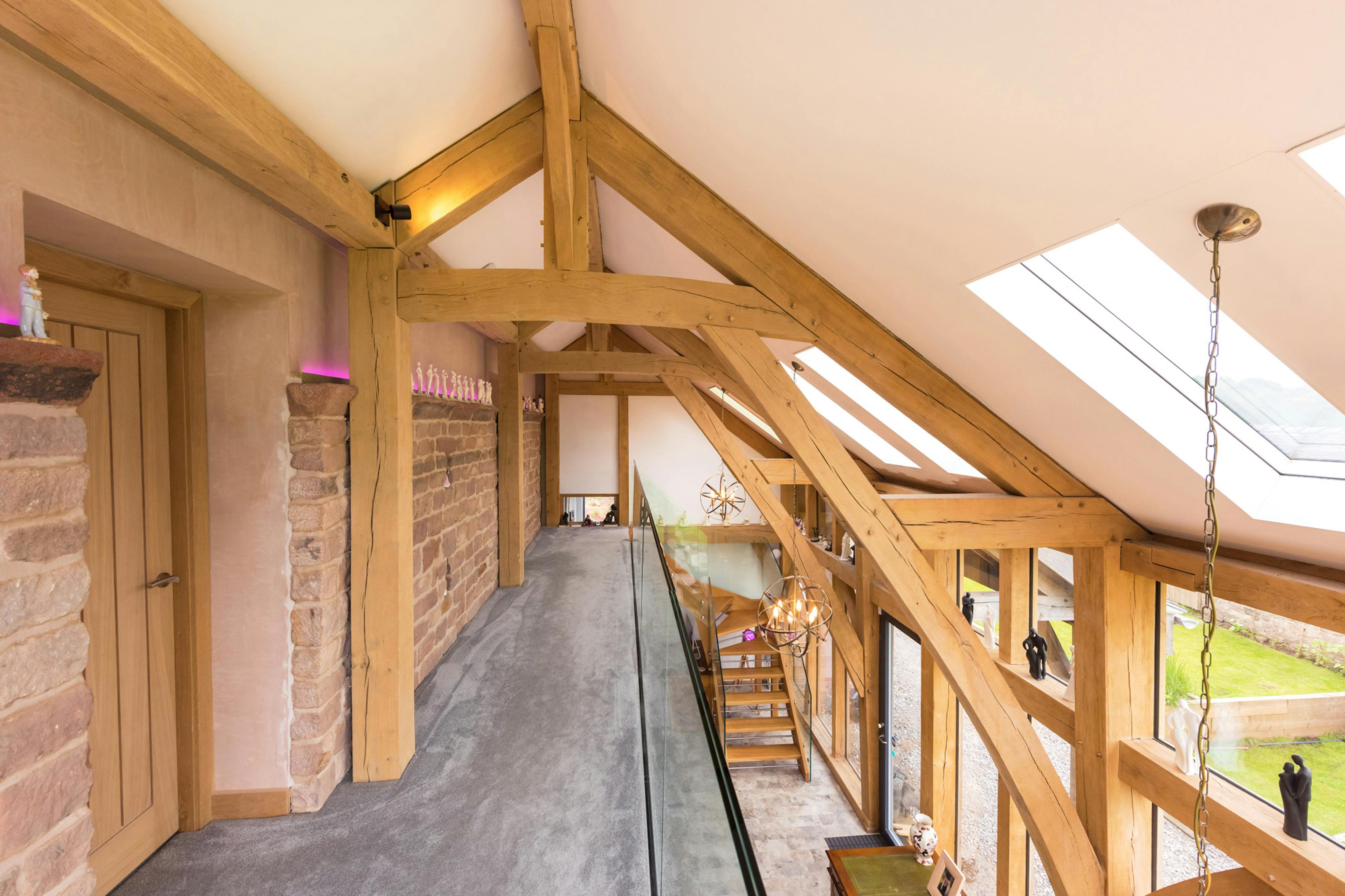 Interior view of the top floor of a two-story oak-framed lean-to extension featuring structural sling brace trusses.