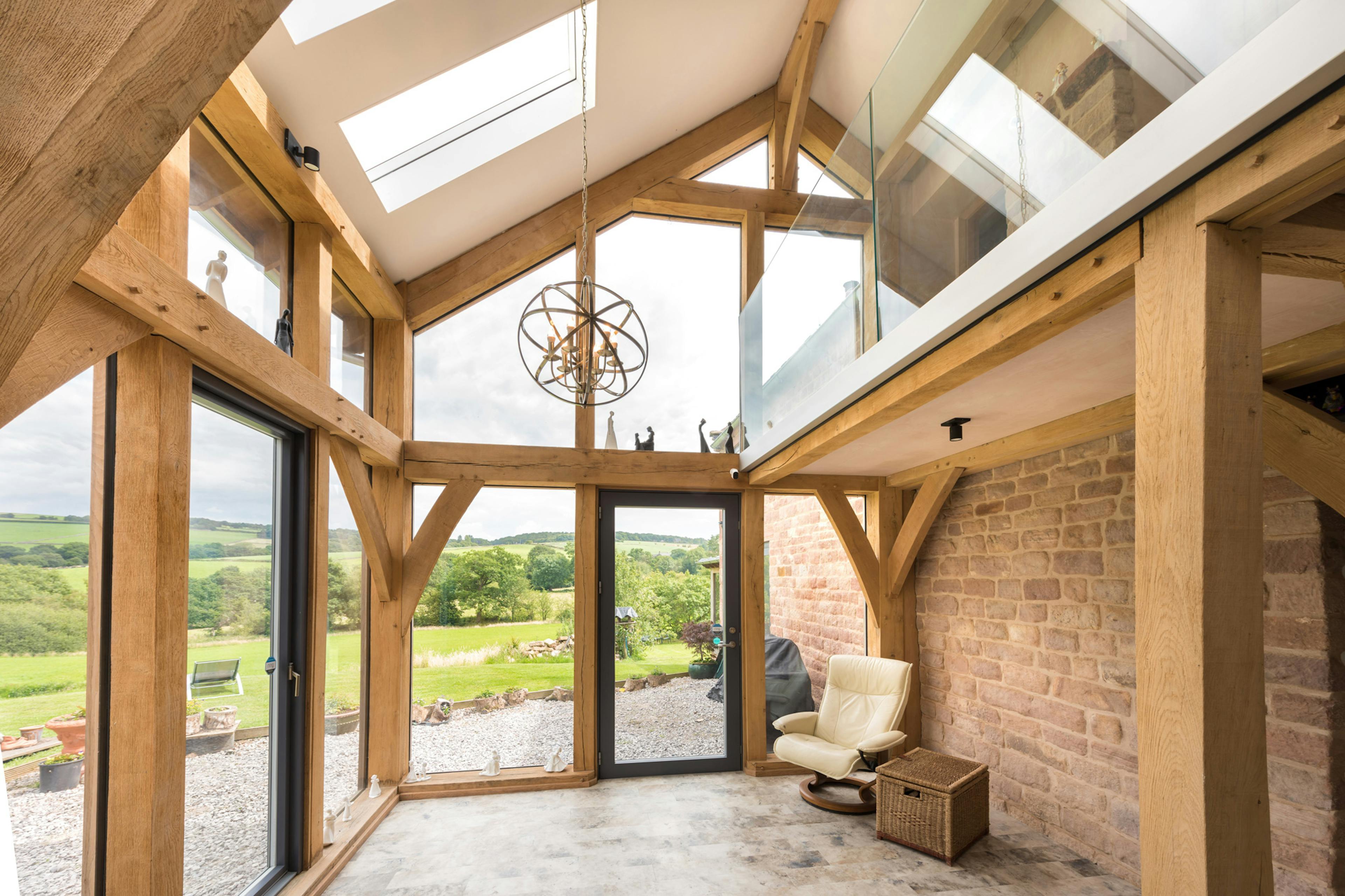 Interior view of a two-story oak-framed lean-to extension featuring direct glazing.