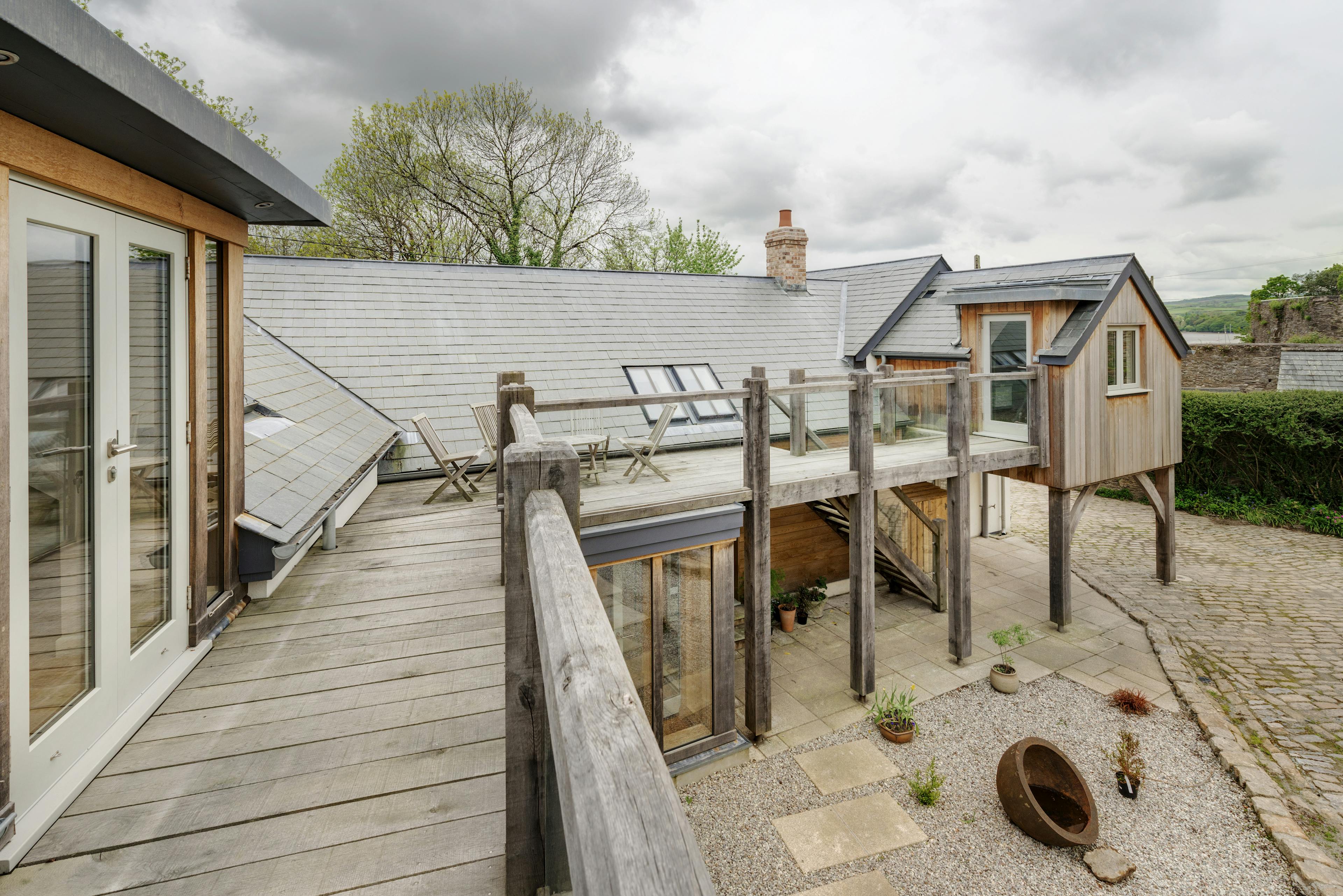 Exterior view of a wrap-around oak-framed balcony on a two-story home overlooking courtyard
