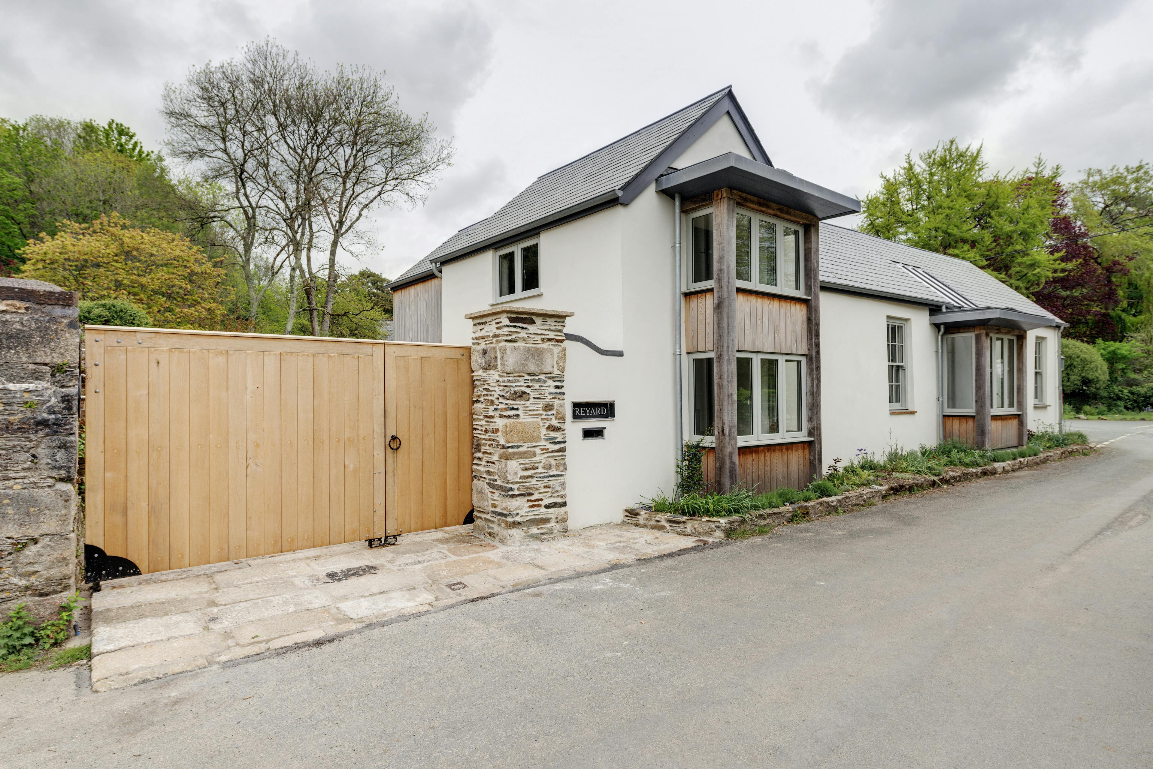 Exterior view of a six-bedroom, two-story oak-framed home situated beside the Tamar River in Devon