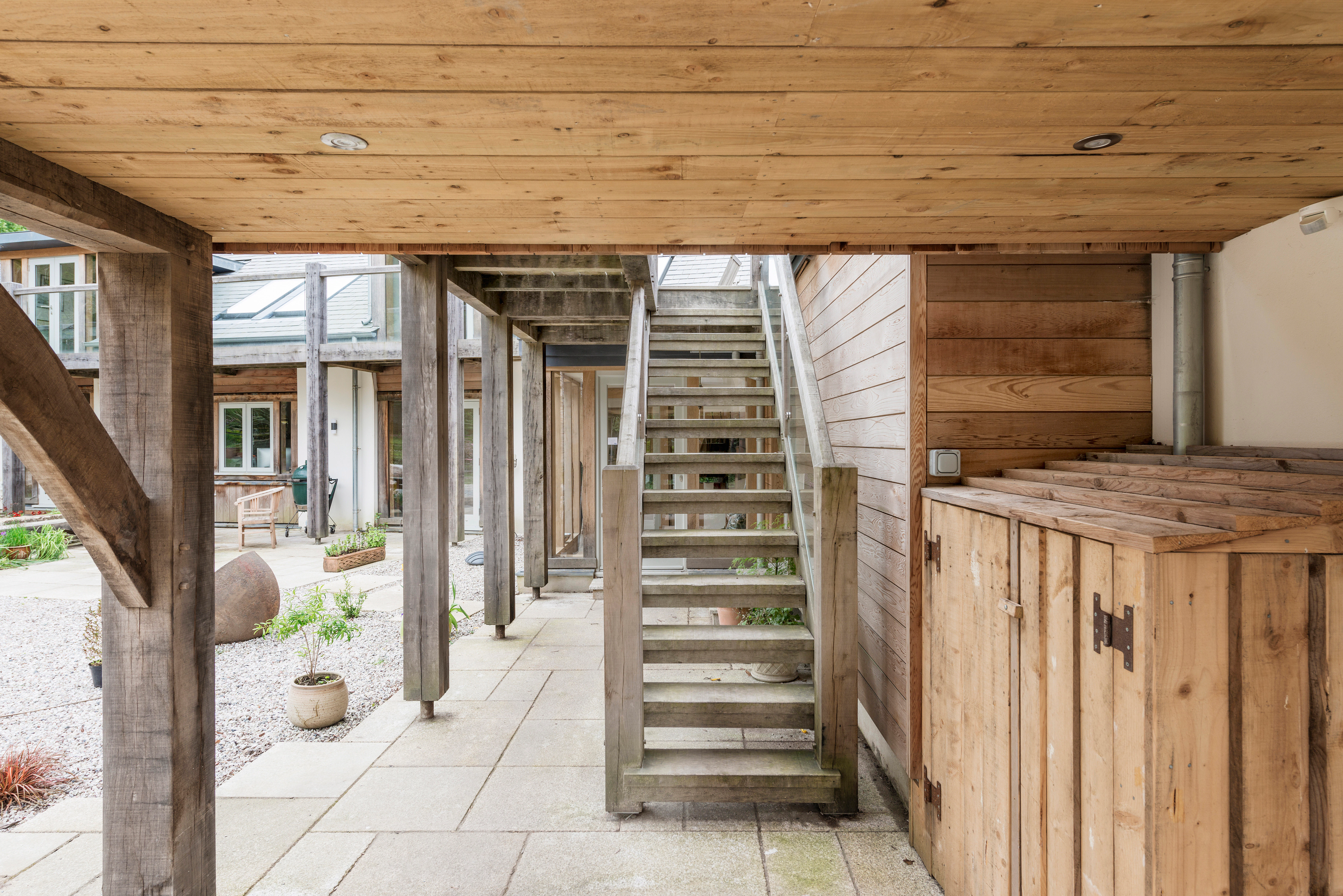 Exterior view of a staircase ascending to a wrap-around oak-framed balcony