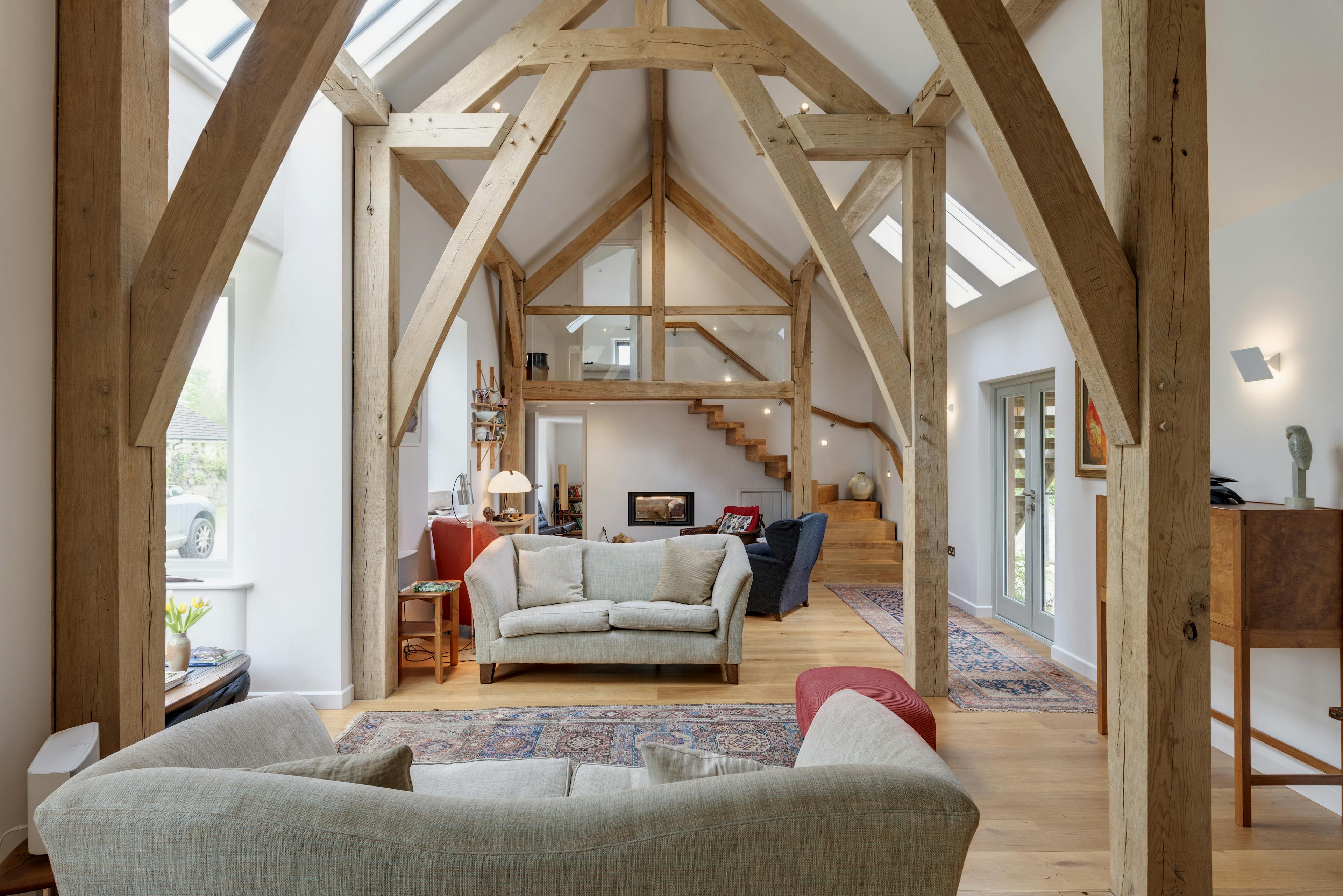 Interior view of an open-plan living area featuring exposed structural oak cruck frame trusses