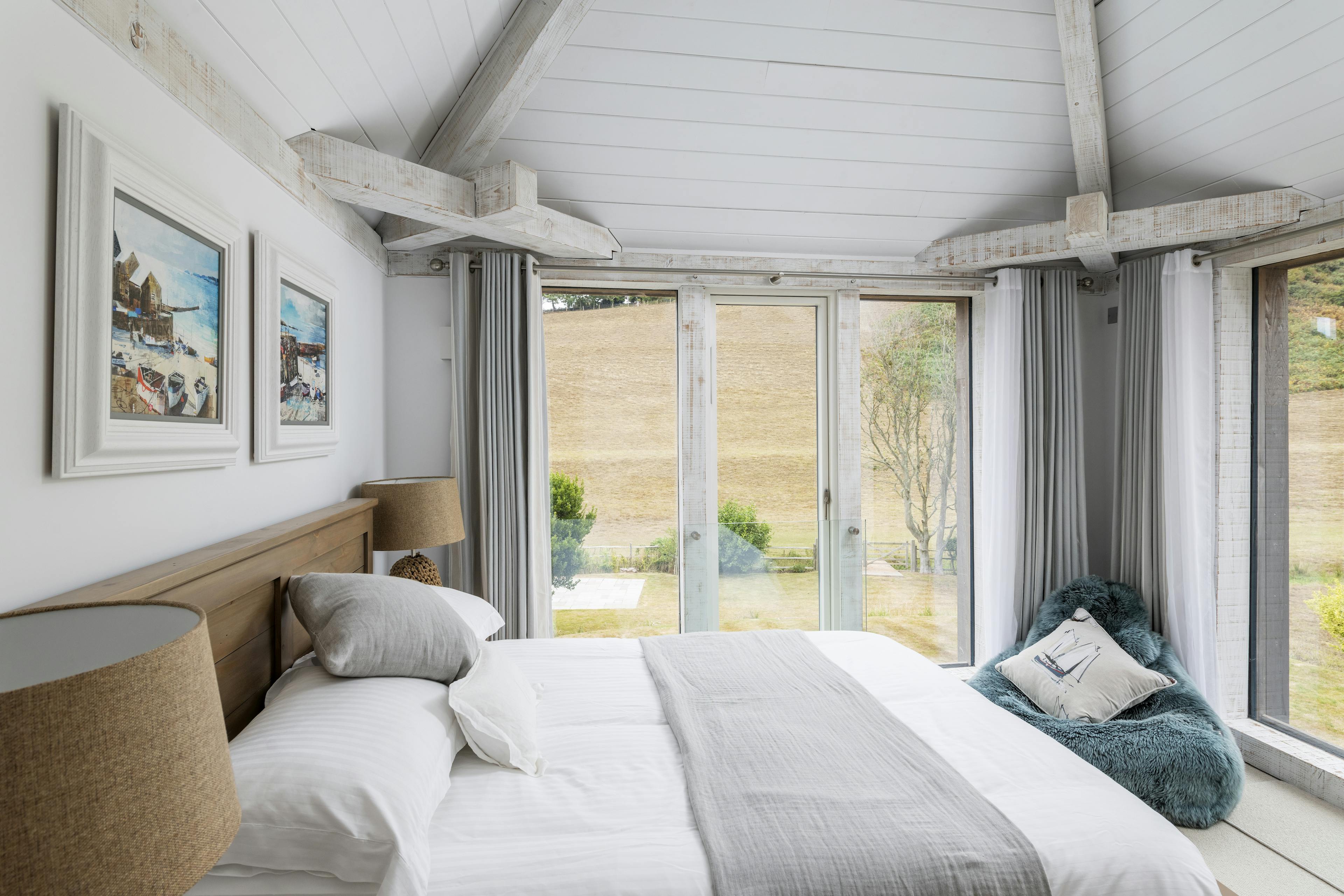 A modern painted Douglas fir framed bedroom with views of fields