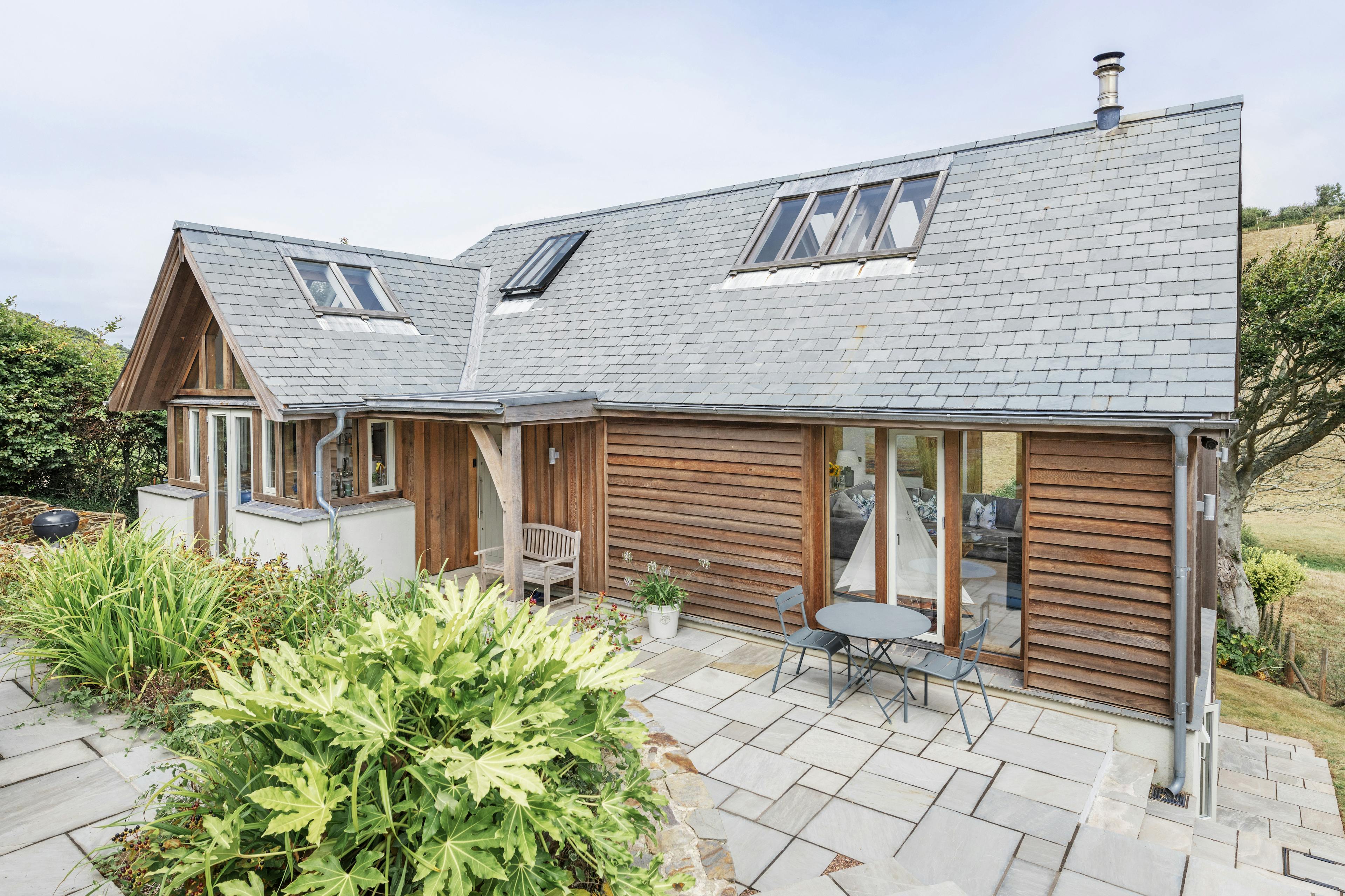 A timber clad home with a patio area outside
