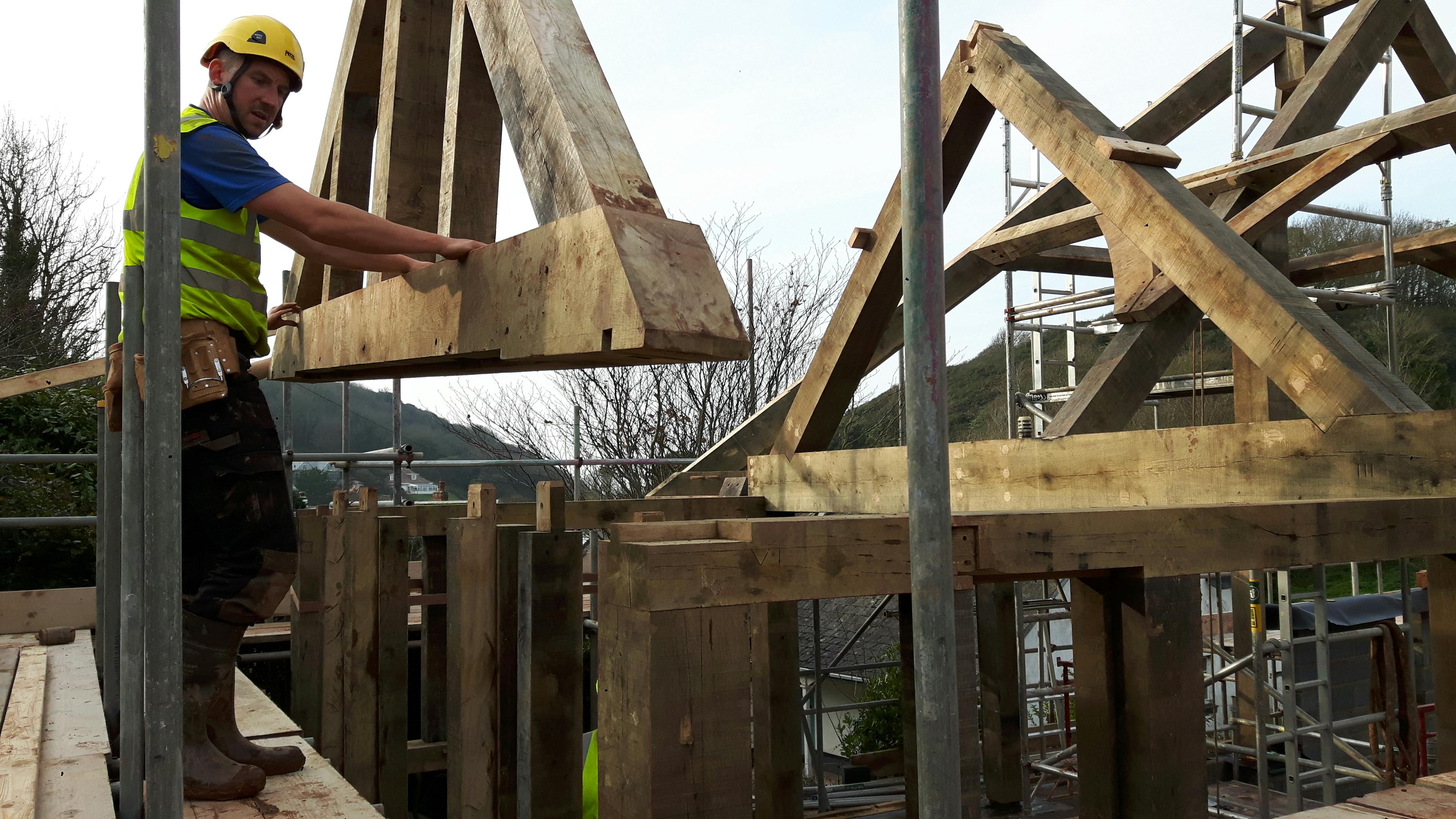 An oak frame being installed by a carpenter on a building site