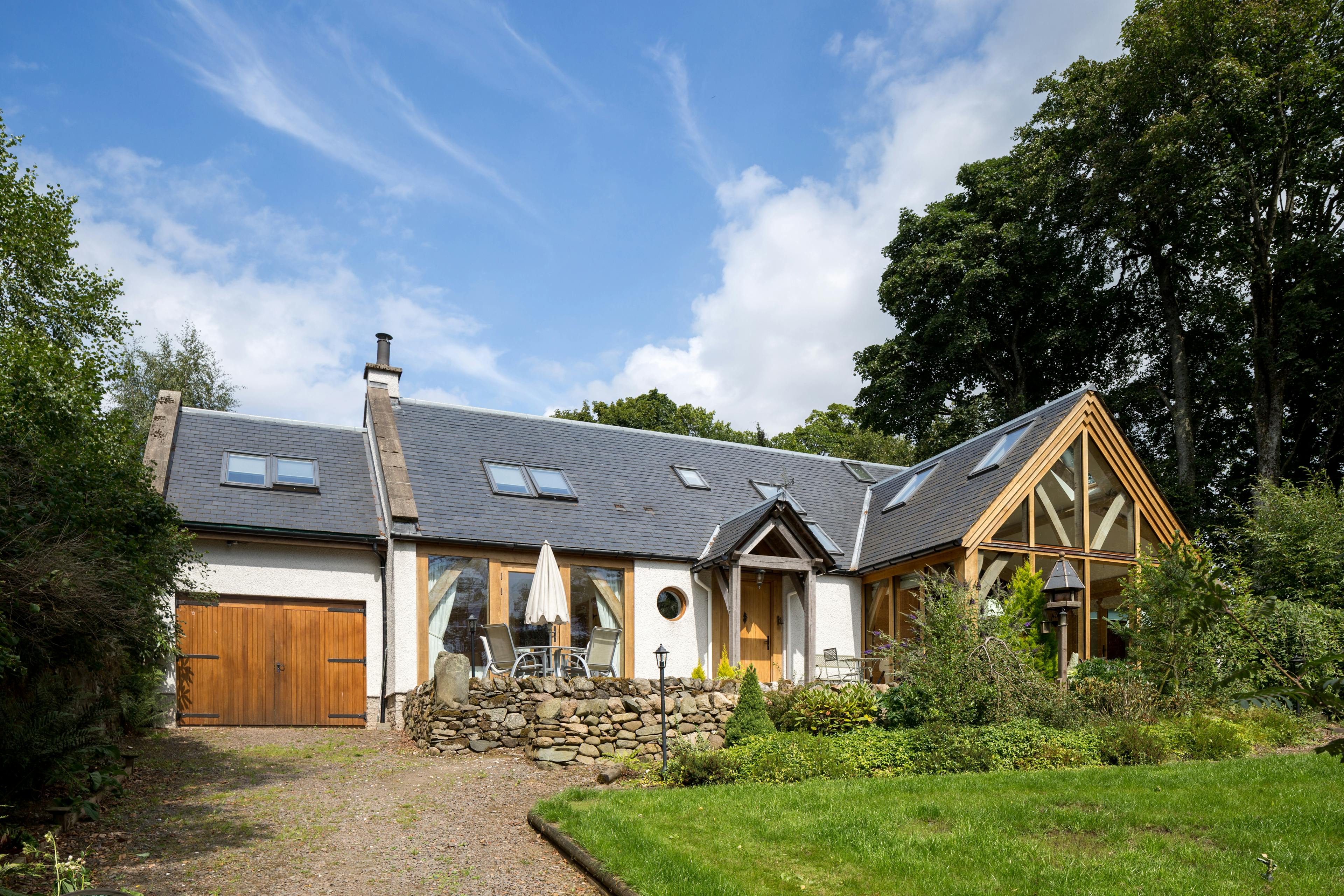 An image of an oak frame home showing a glazed gable, tiled pitched roof, and oak porch