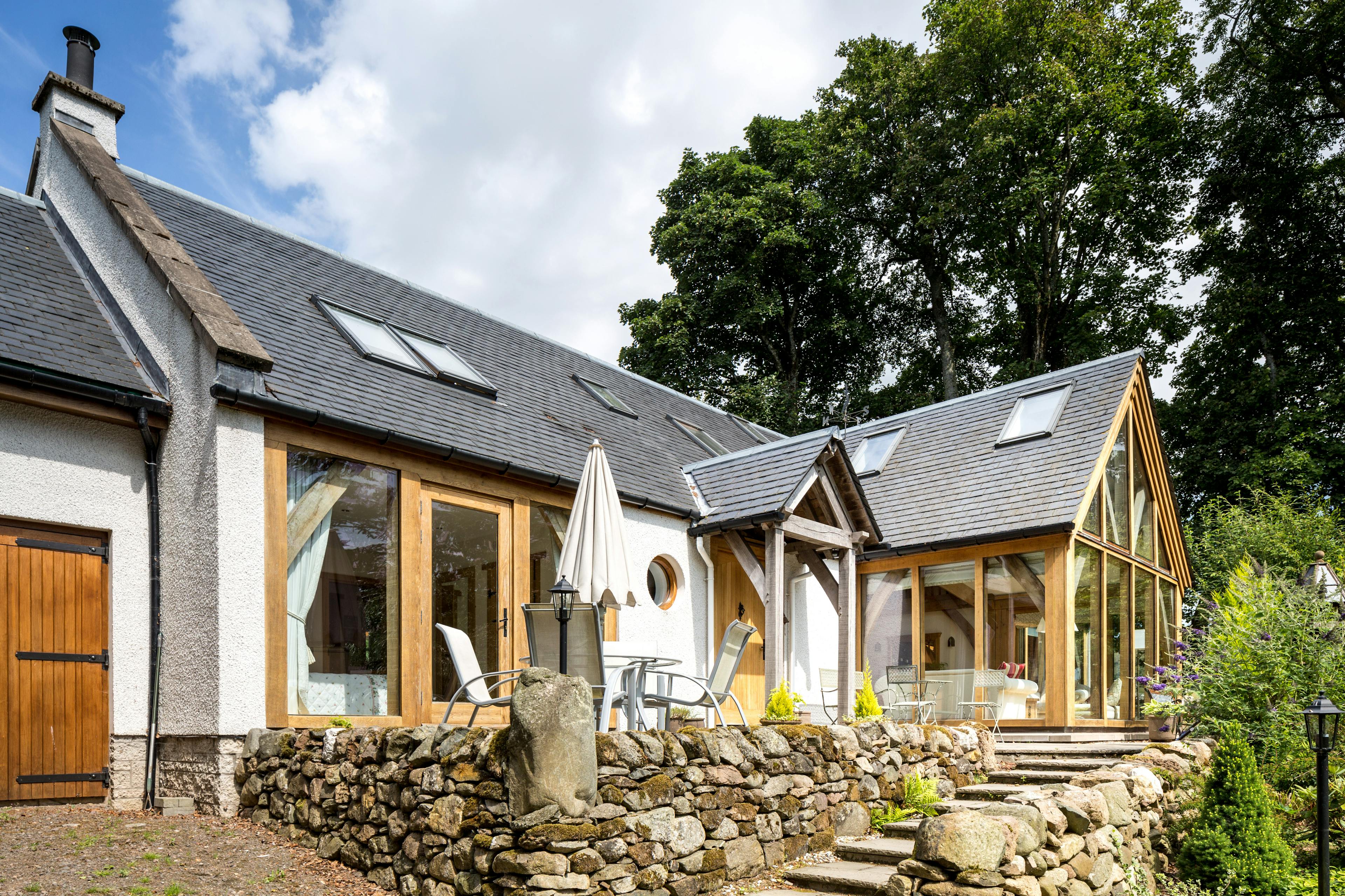 An image of an oak frame home showing a glazed gable, tiled pitched roof, and oak porch