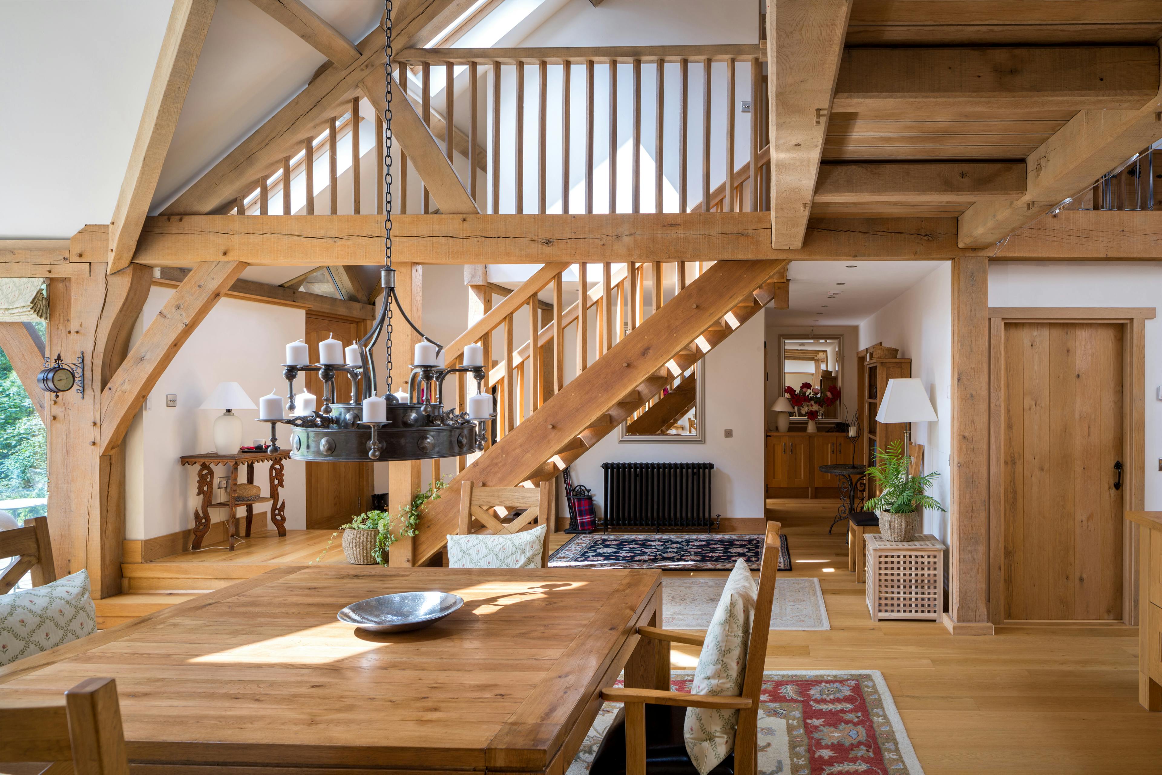 Oak framed living area with a dining table and a wooden staircase