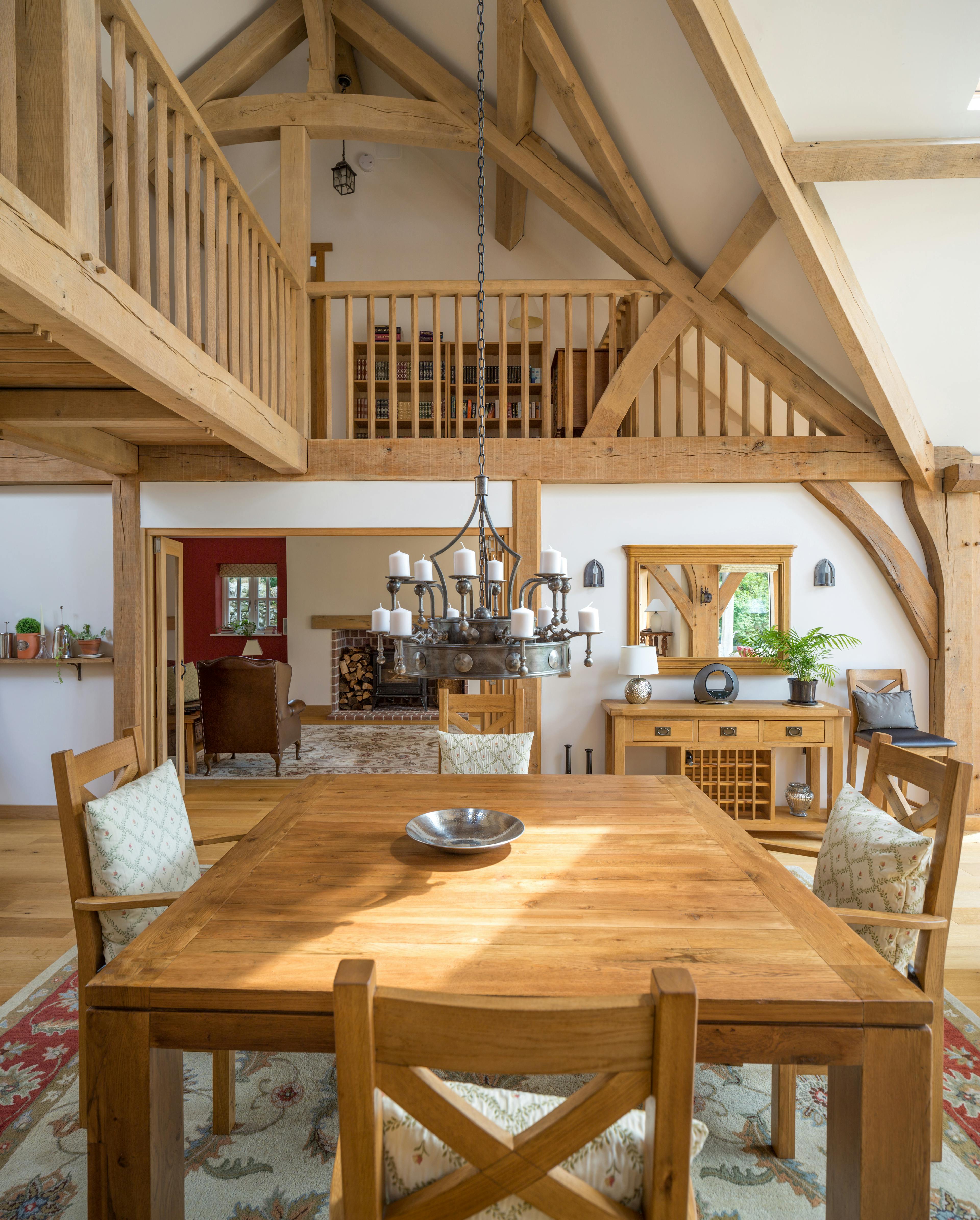 An oak framed home showing a dining table below a wooden linking bridge