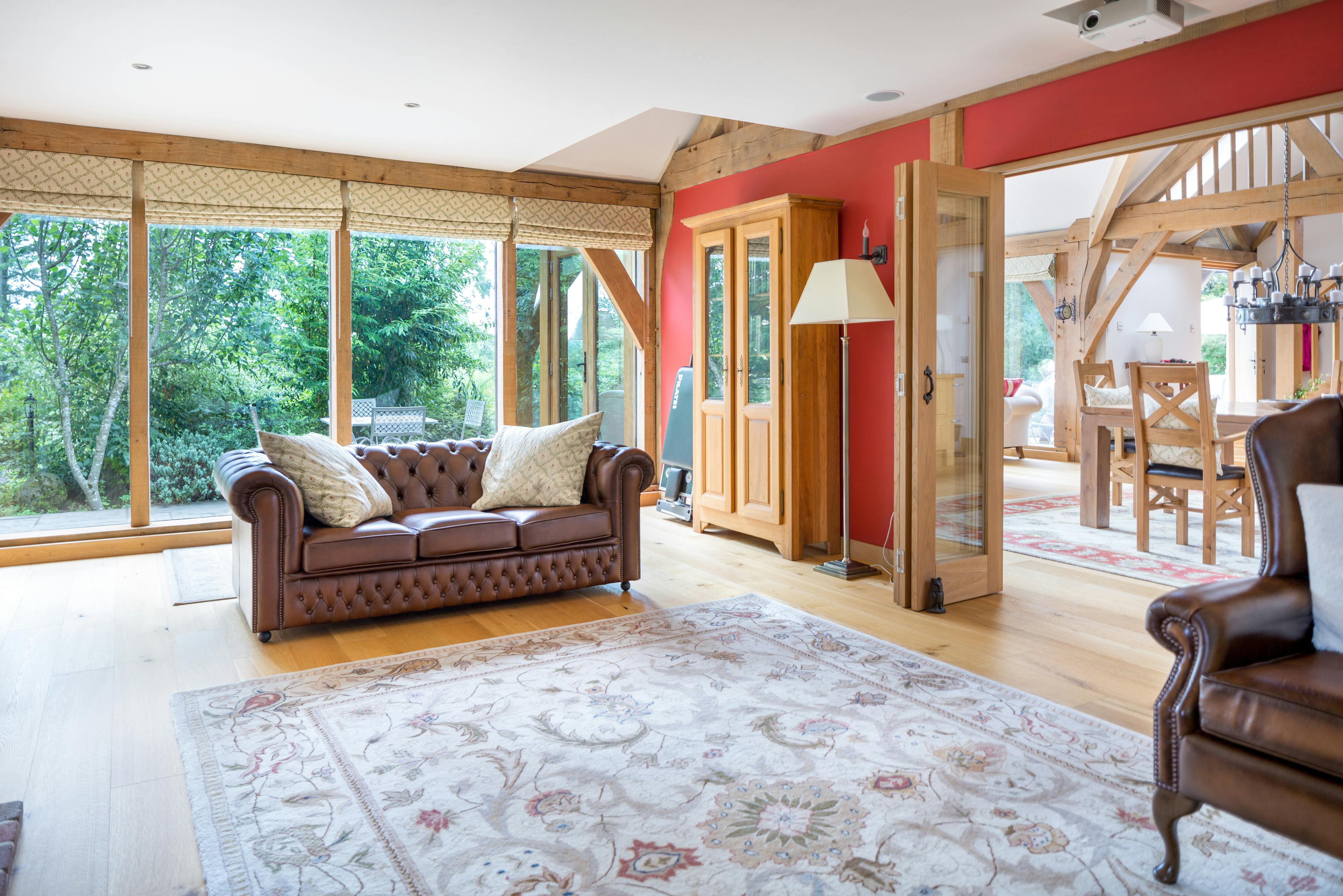 An oak framed sitting room with large floor to ceiling windows and folding doors which connect the room to the dining area