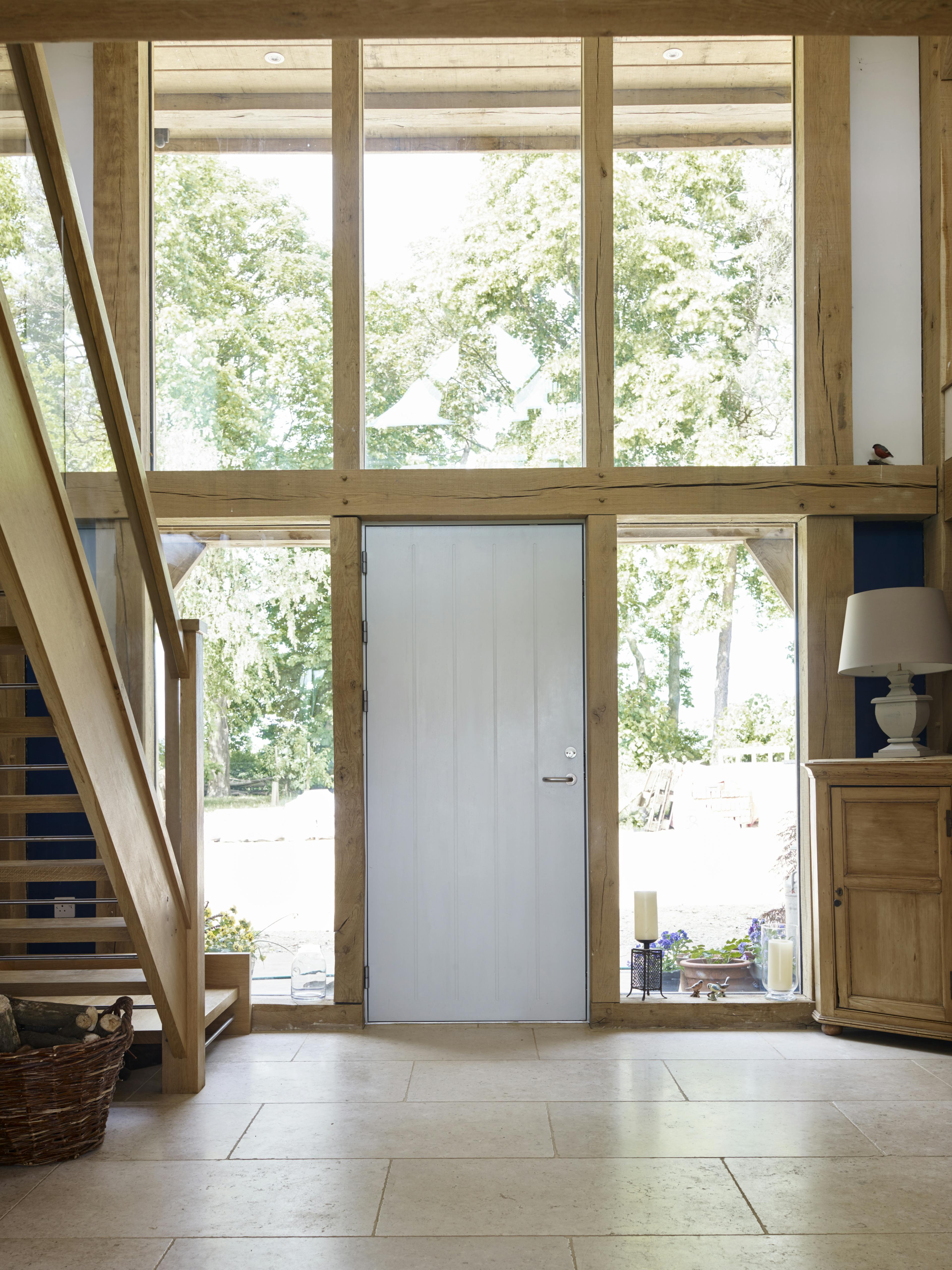 An oak framed double-height light entrance hall with wooden stairs