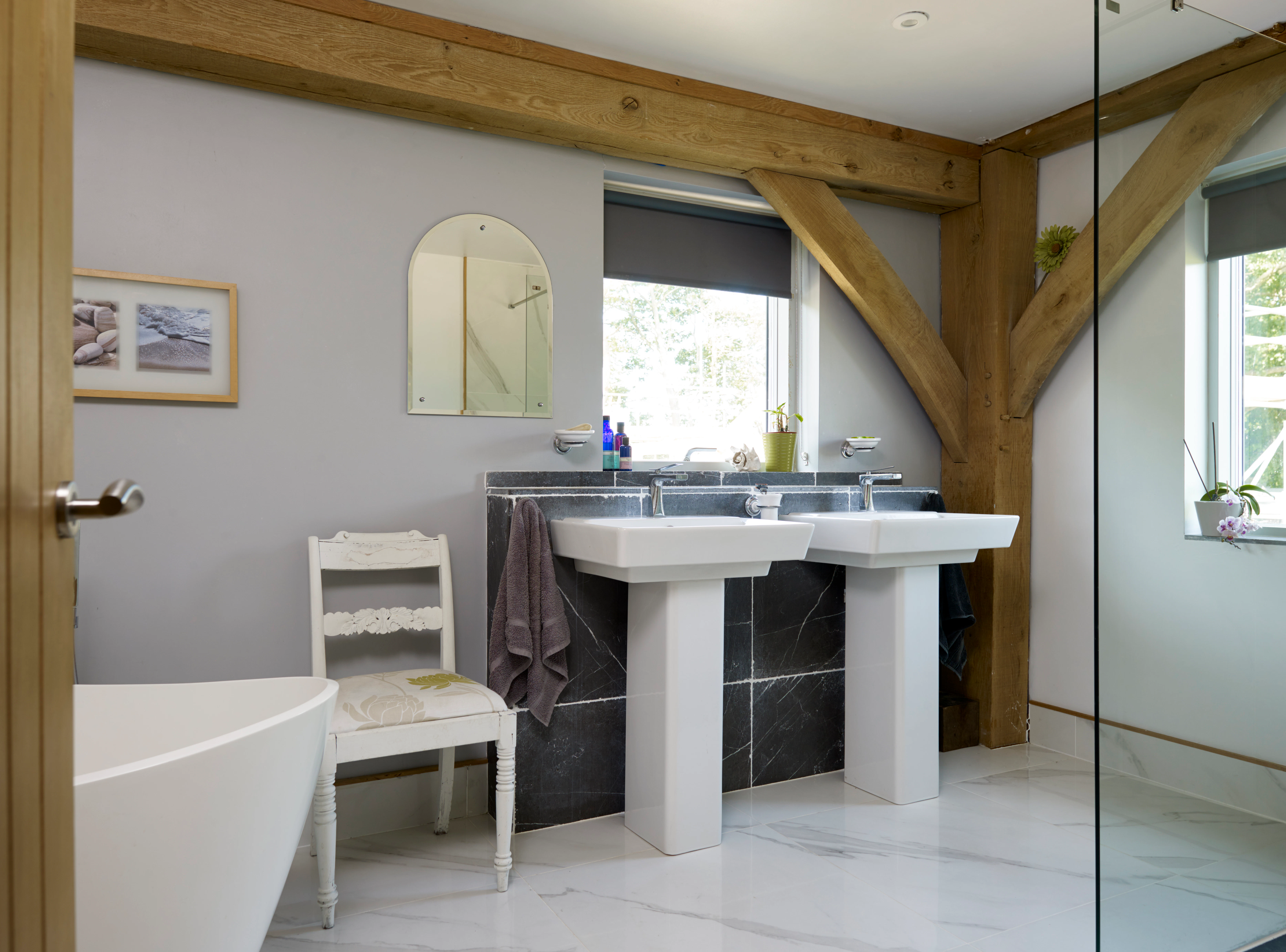 An oak framed bathroom showing double sinks and white bath