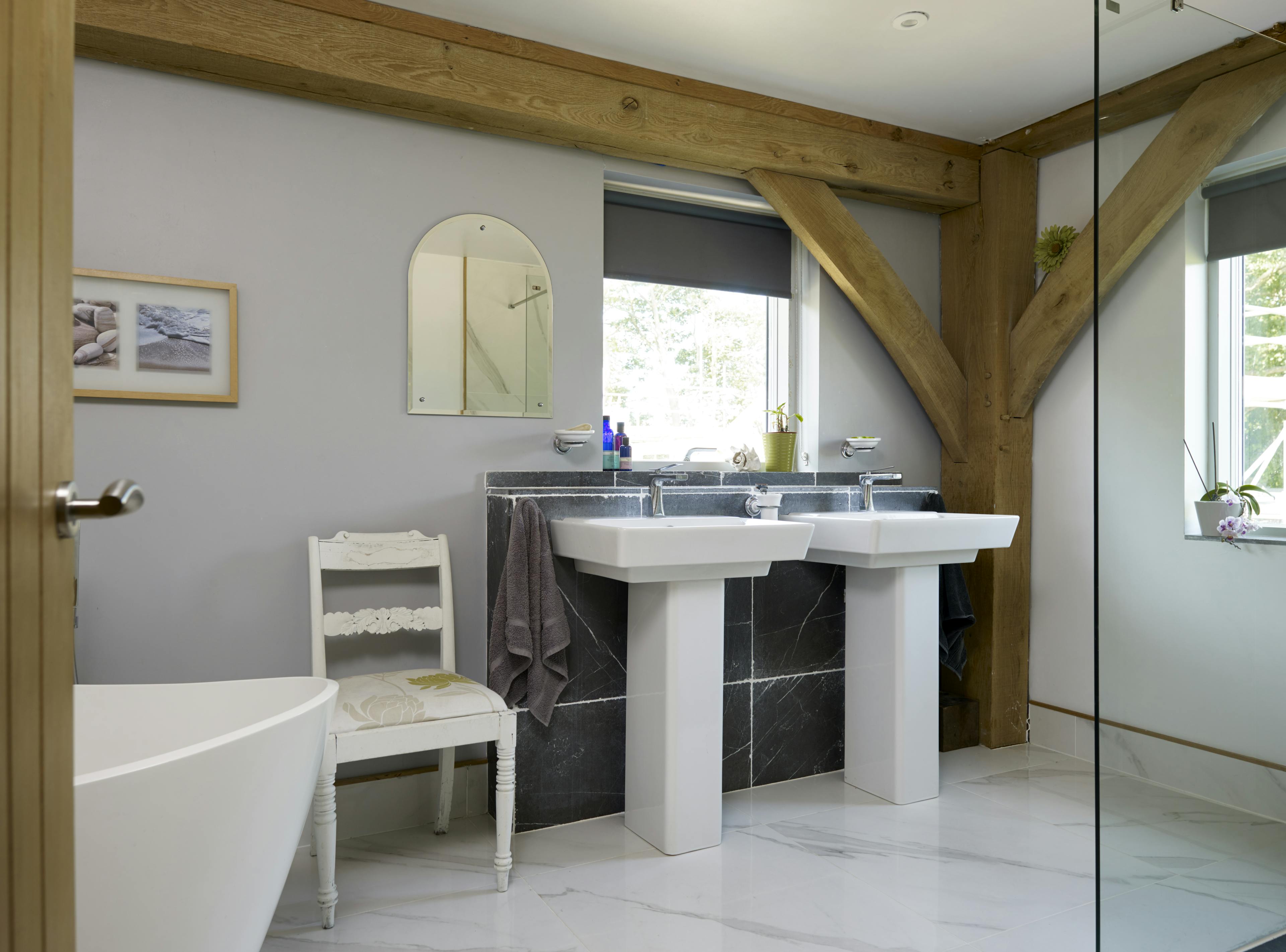 An oak framed bathroom showing double sinks and white bath