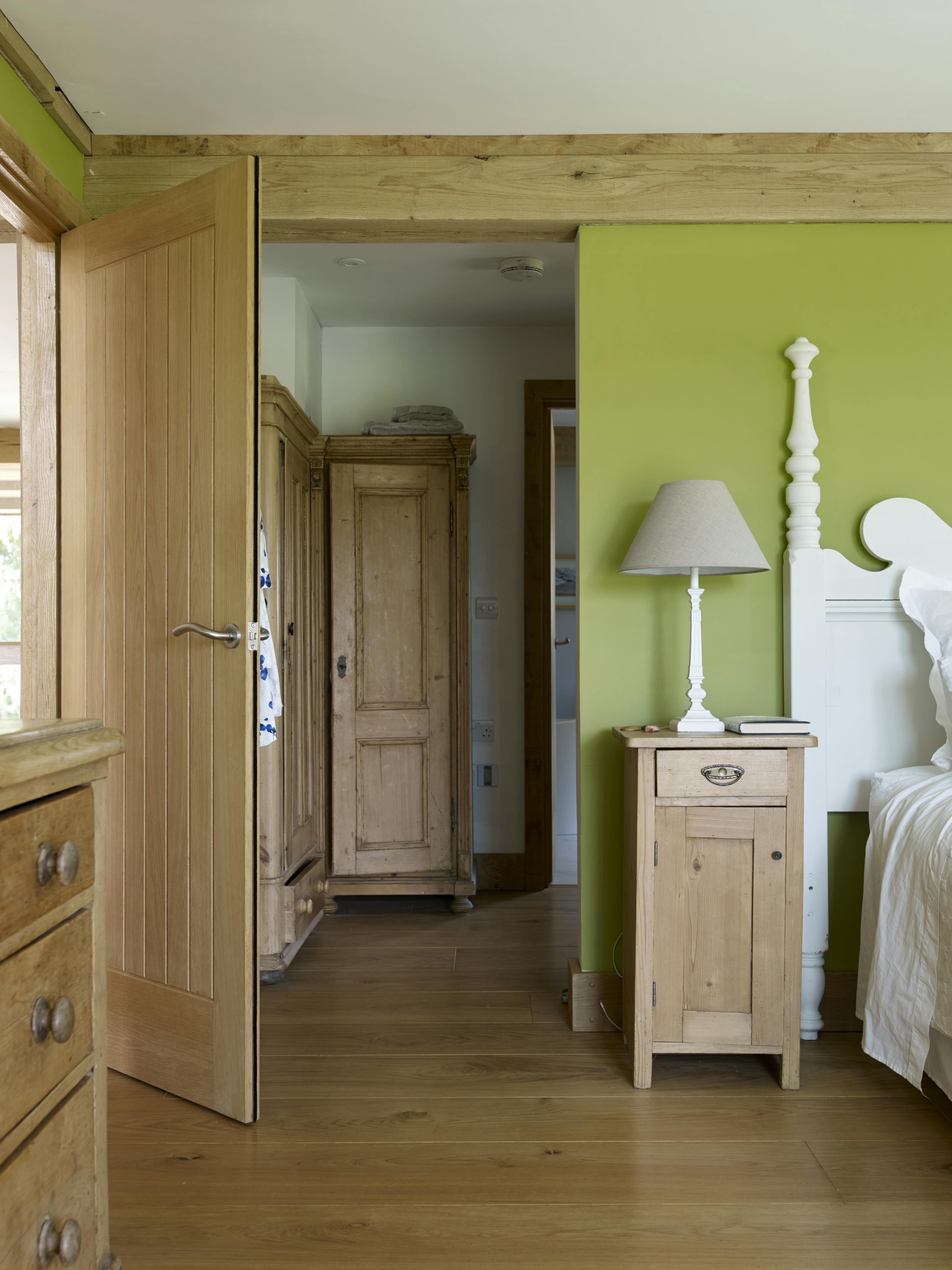 An oak framed bedroom showing wooden bedside table, wardrobe and chest of drawers