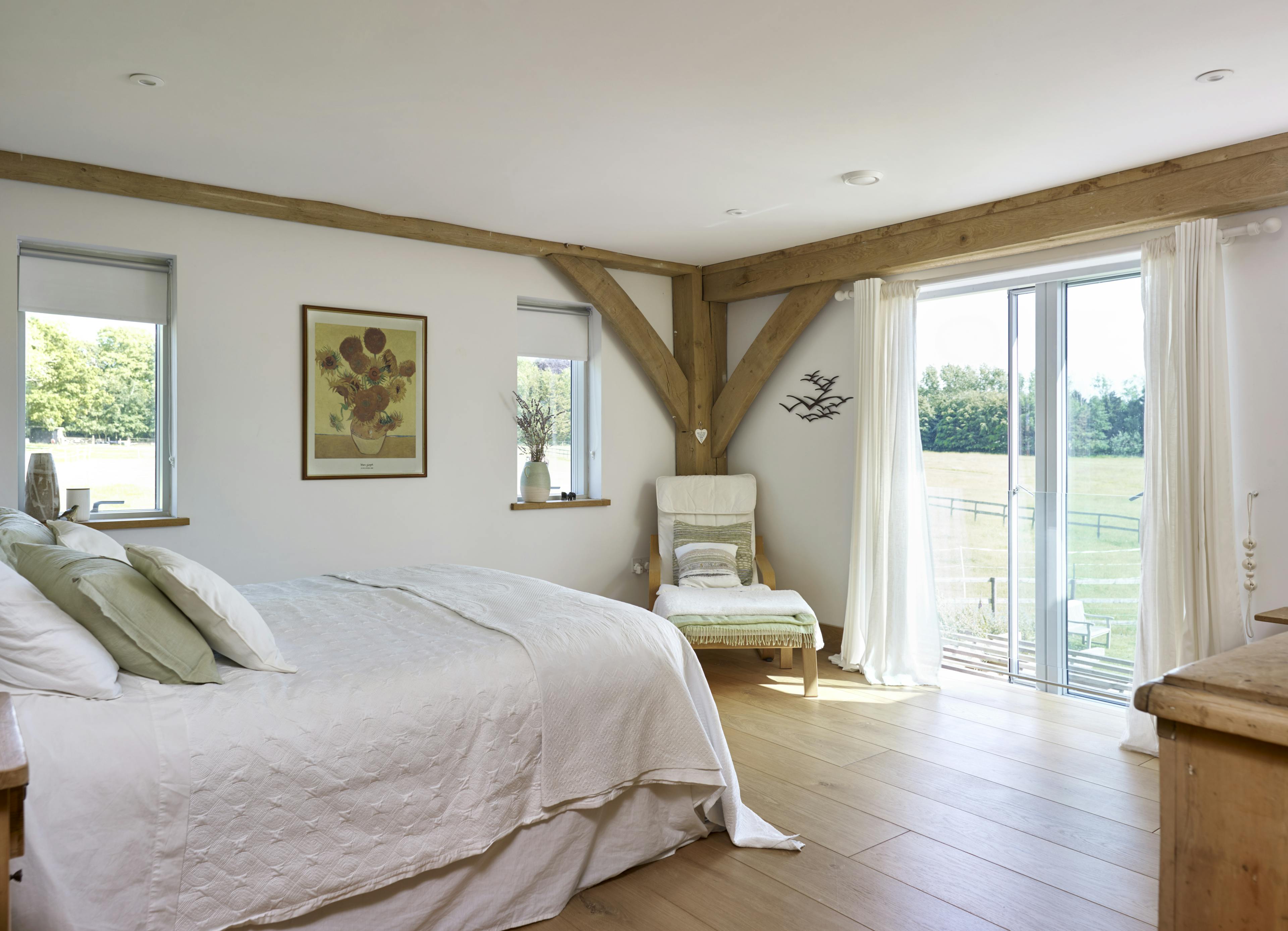 An oak framed bedroom with sliding doors to a garden