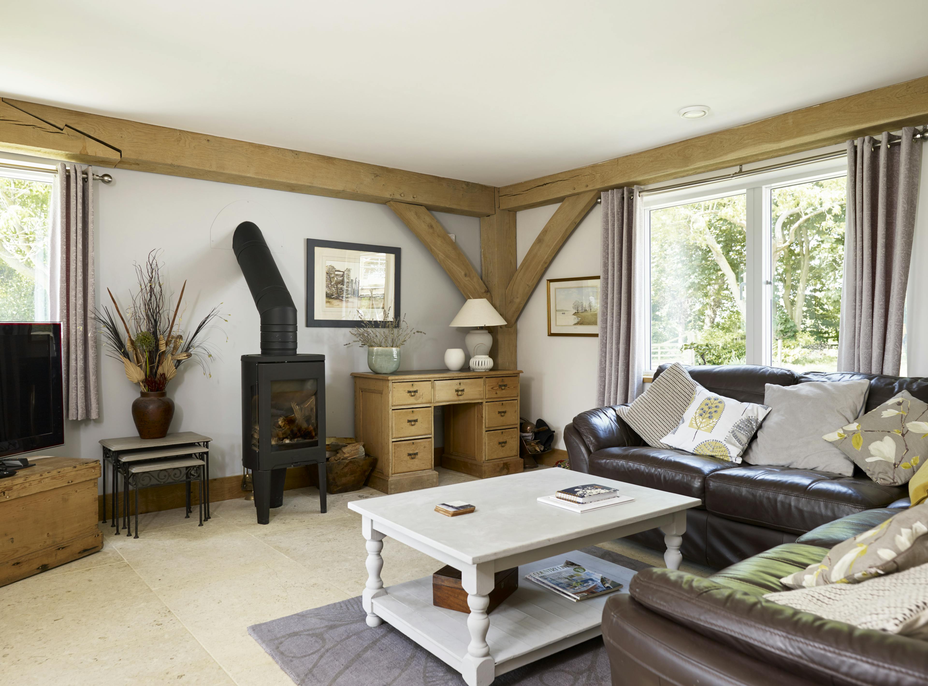 An oak framed living room with sofas and a log burner