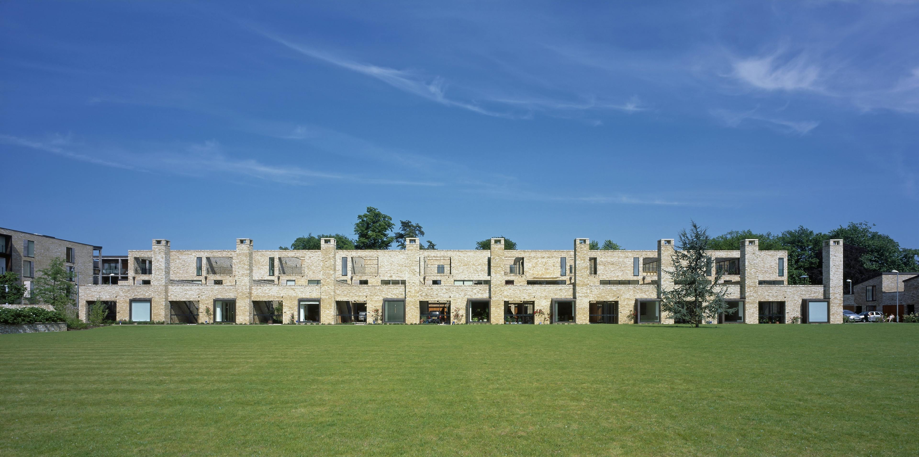 Exterior view of a housing project featuring unique oak-framed grids that support modular balconies made of timber, steel, and glass.