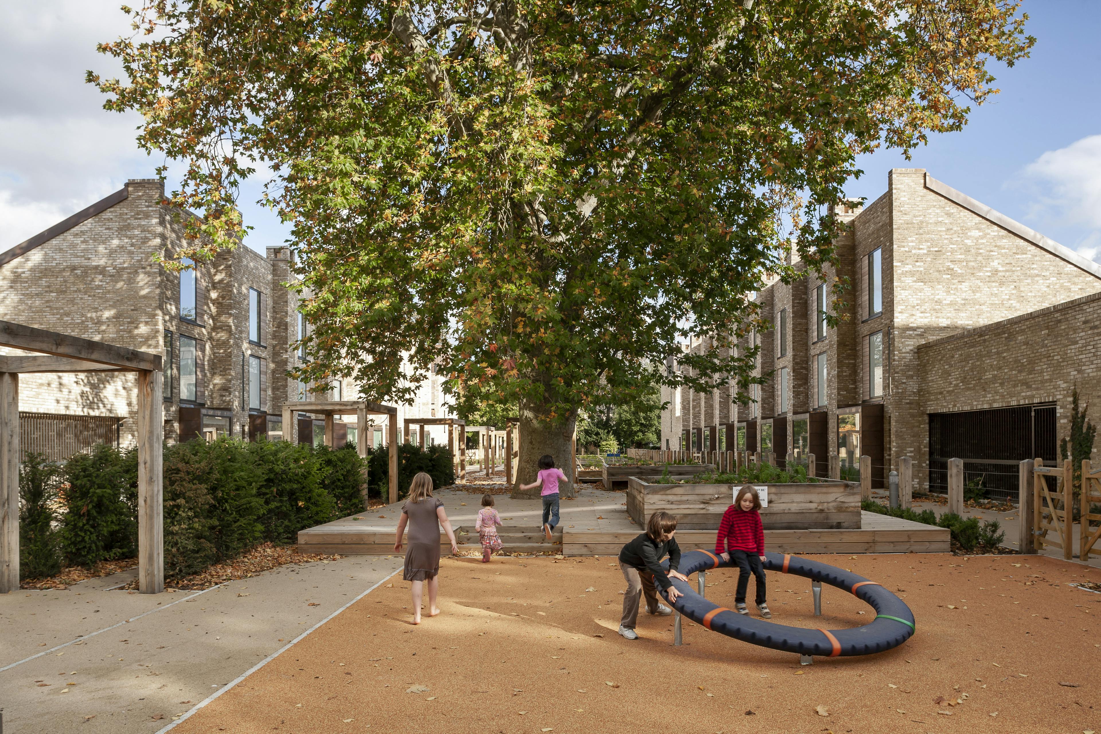 Exterior view of contemporary houses and apartments featuring public gardens and a communal playground.