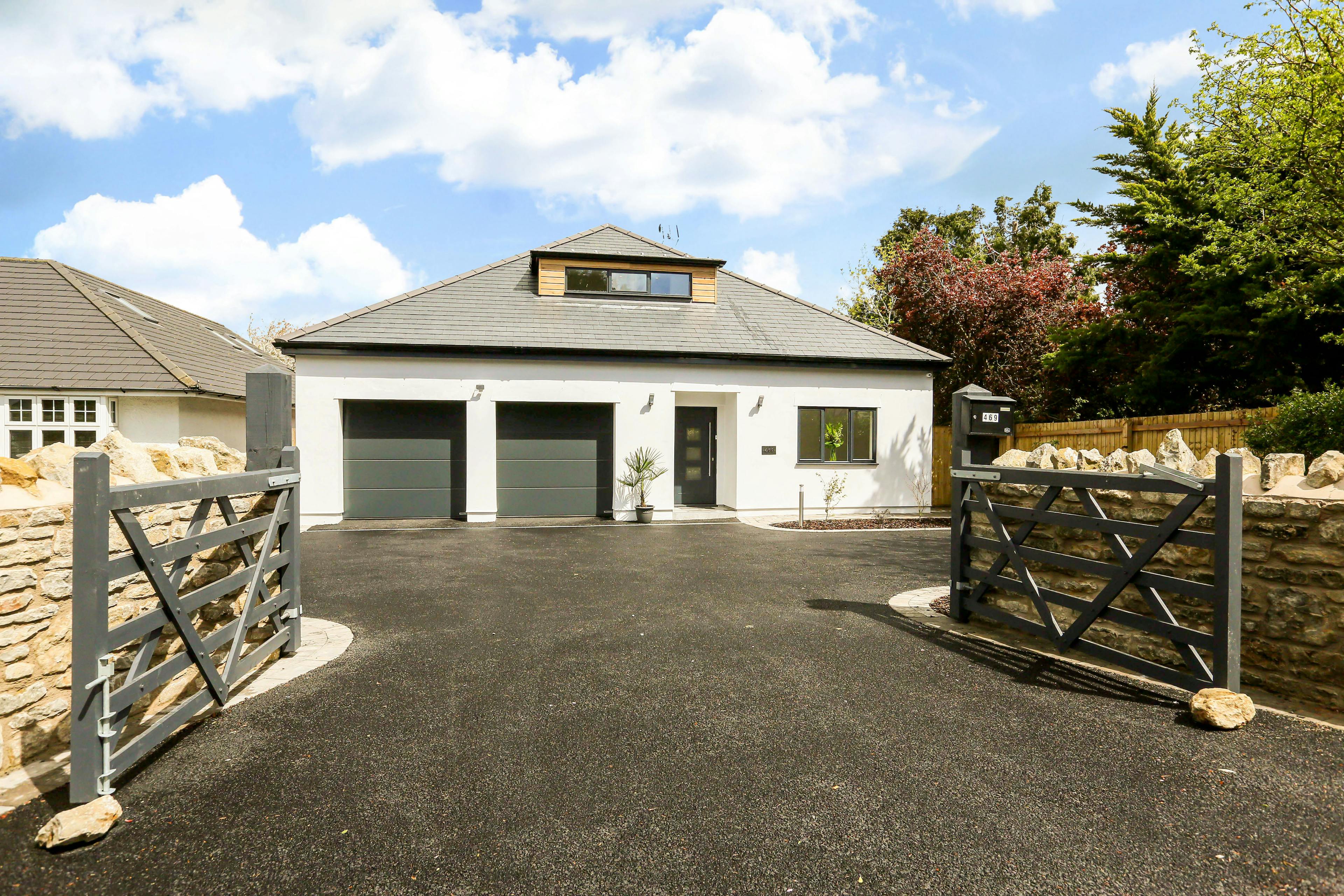 The front of a modern white house with a driveway and 2 built in garages