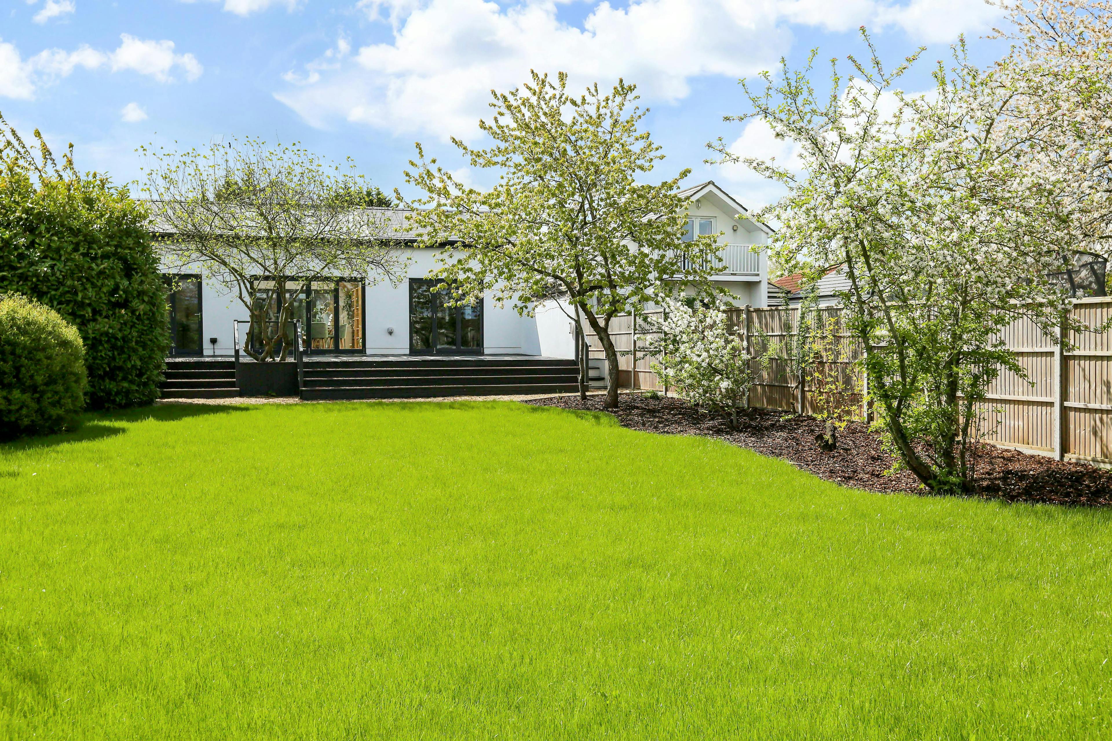 The back of a modern white house with a large lawn in the back garden