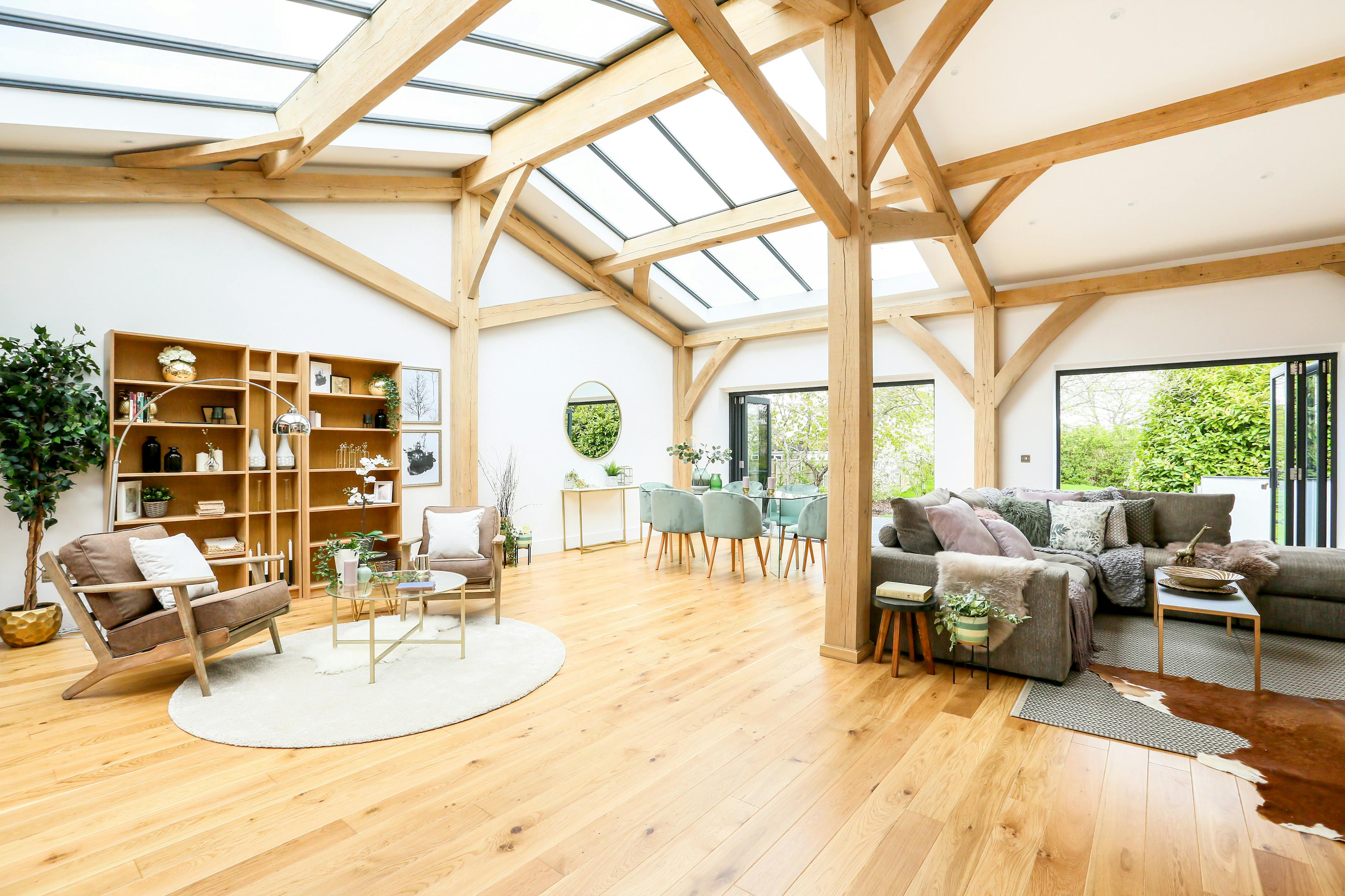 A light filled modern oak frame home with rooflights, showing an open plan living area with armchairs, dining area and sitting area with sofas