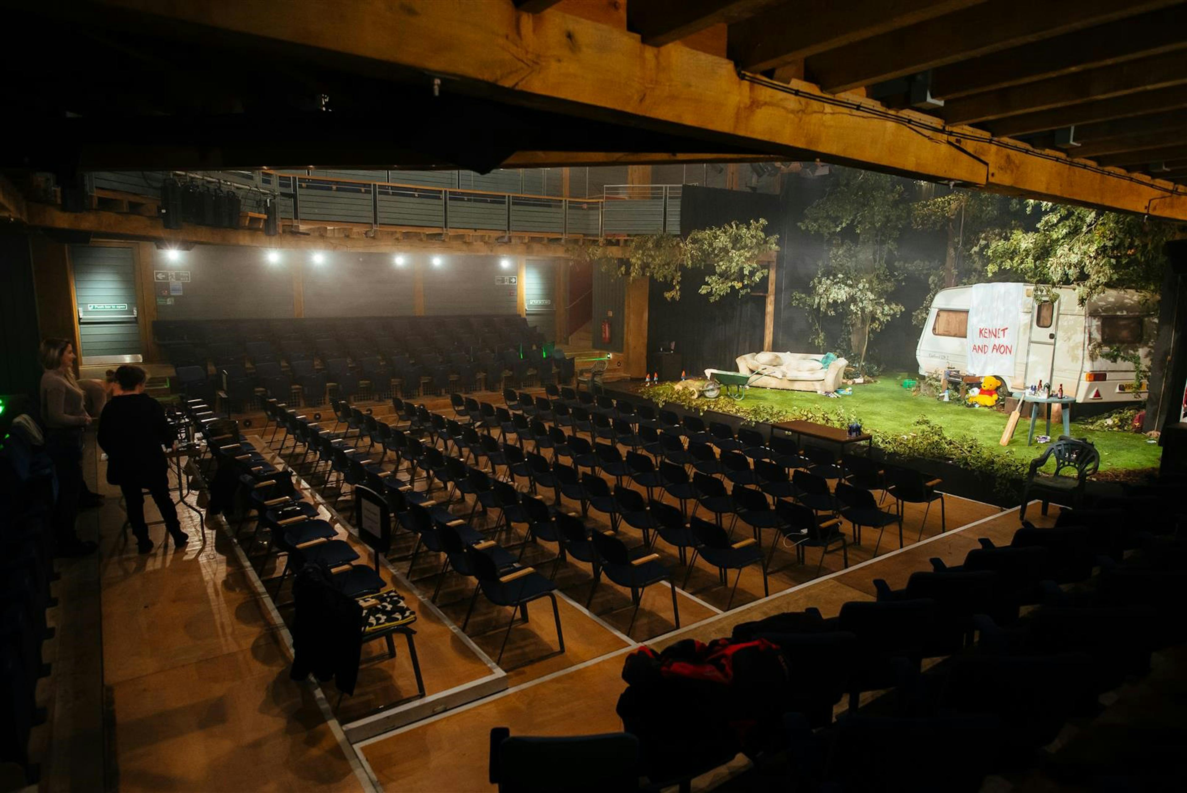 Interior of an oak frame theatre with a stage set up but empty seats