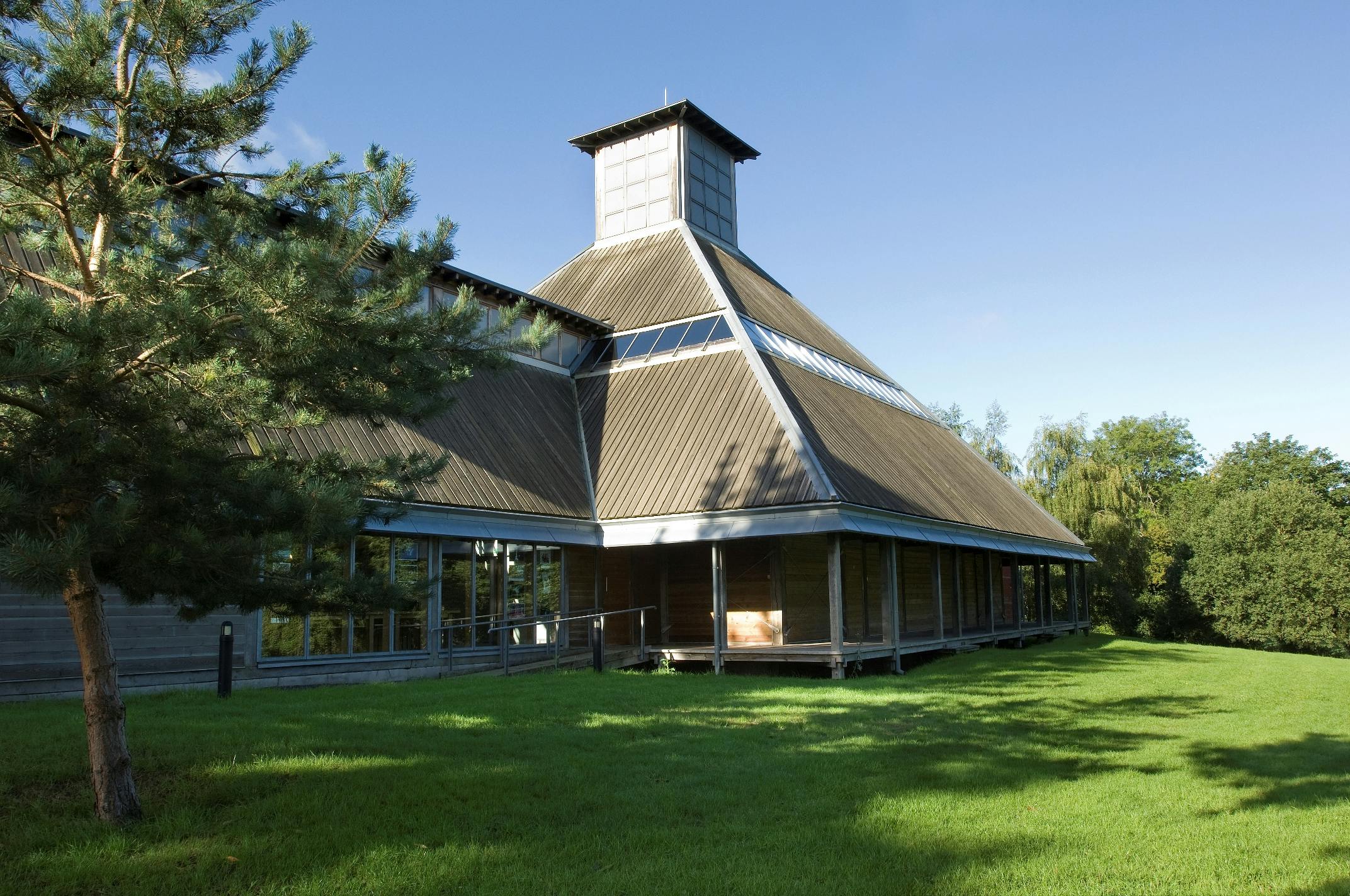 An oak frame theatre with a pyramidal roof lantern, with a lawn in front of it
