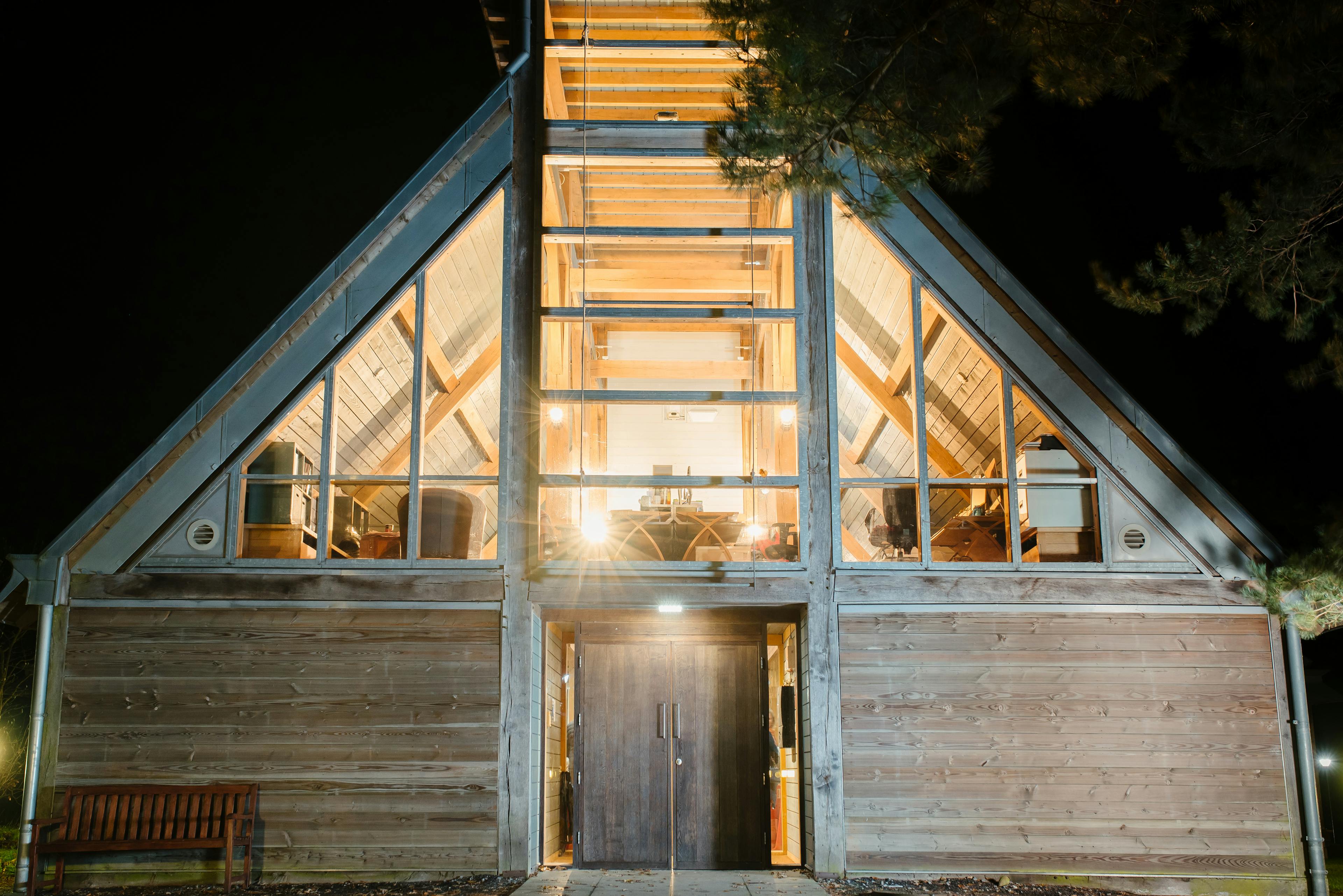 An oak frame theatre with a pyramidal roof lantern, shown at night with lights on 