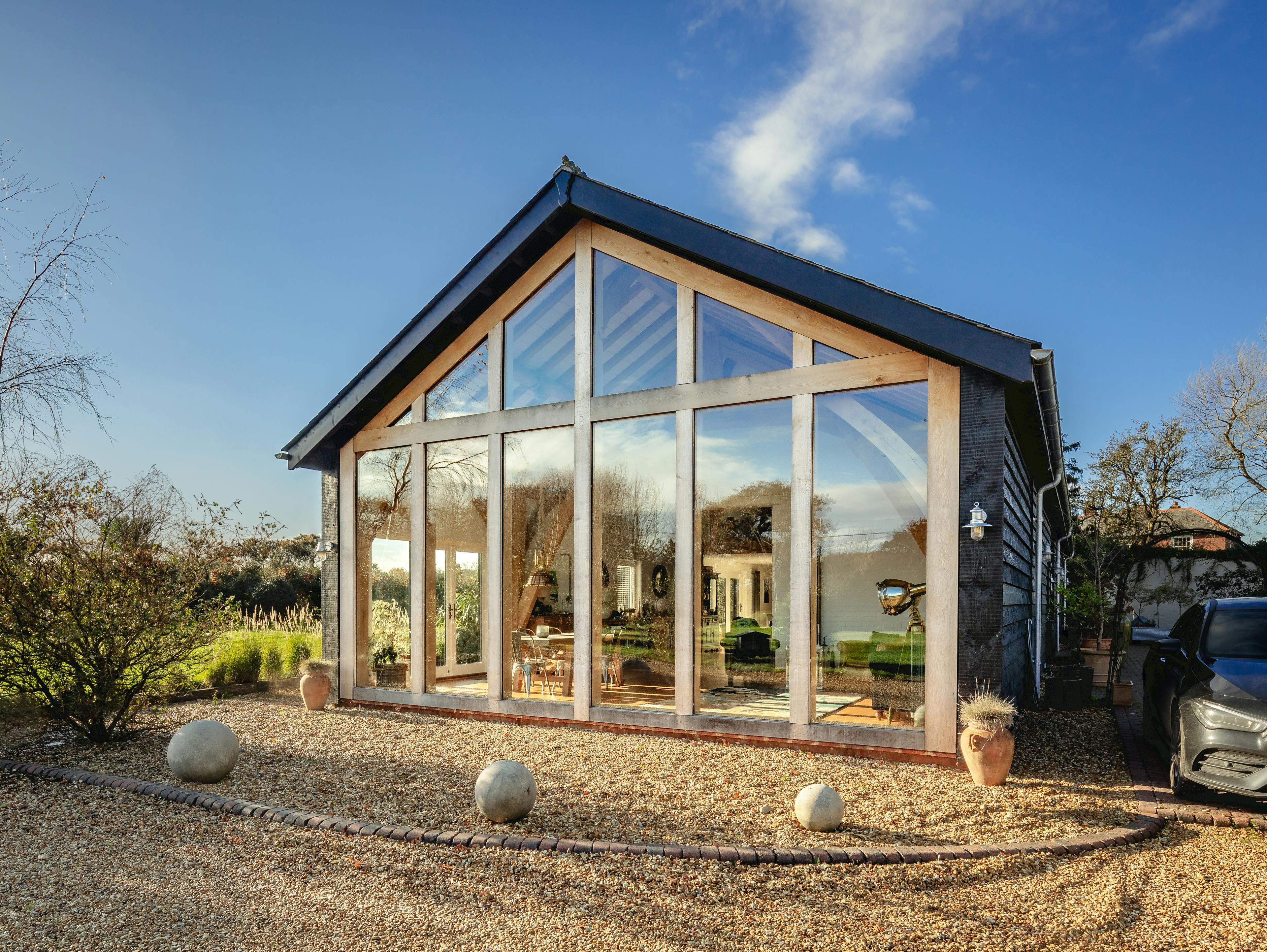 A gravel driveway in front of an oak framed extension with a glazed gable 