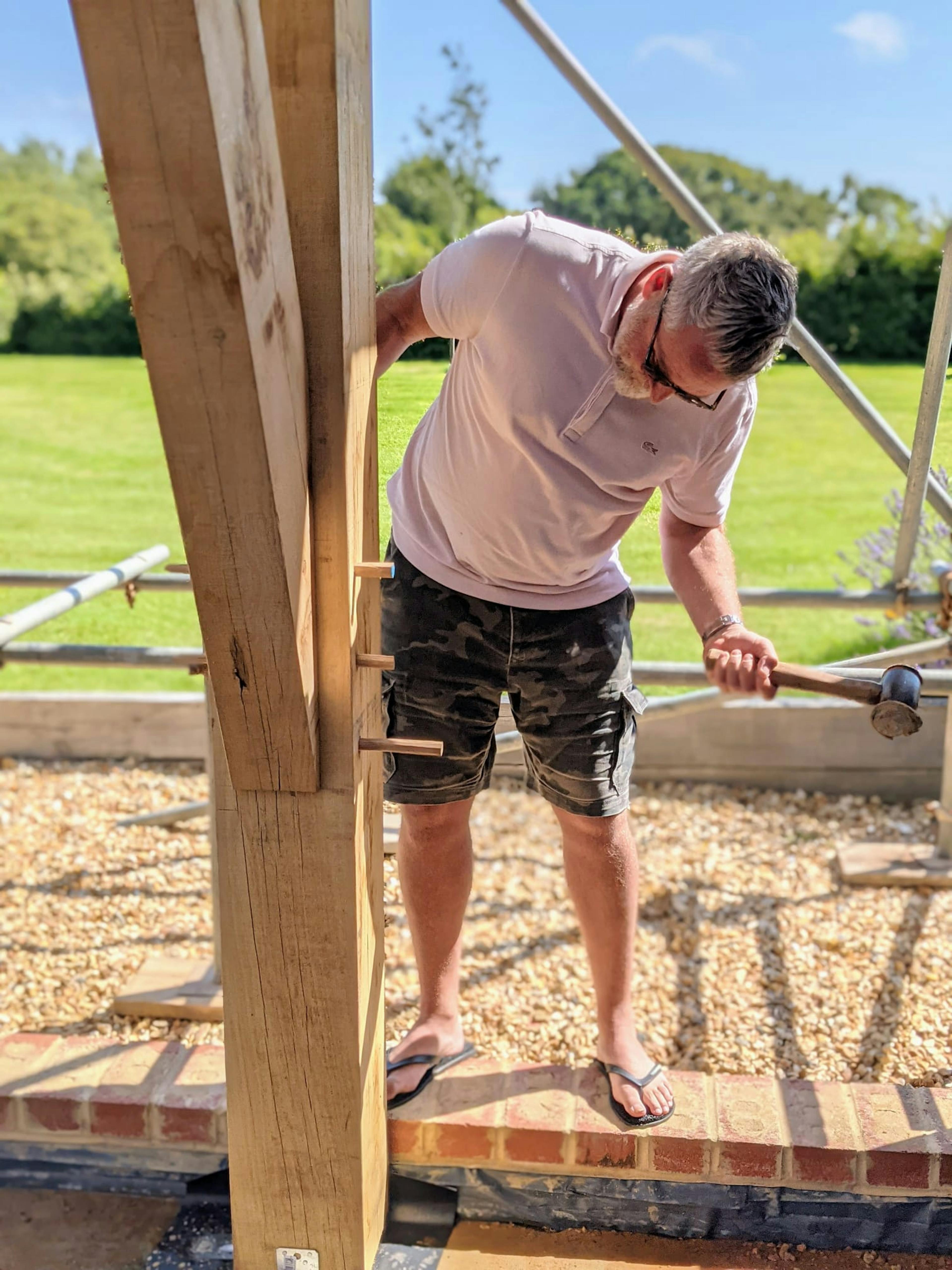 A man hammers a wooden peg into an oak frame