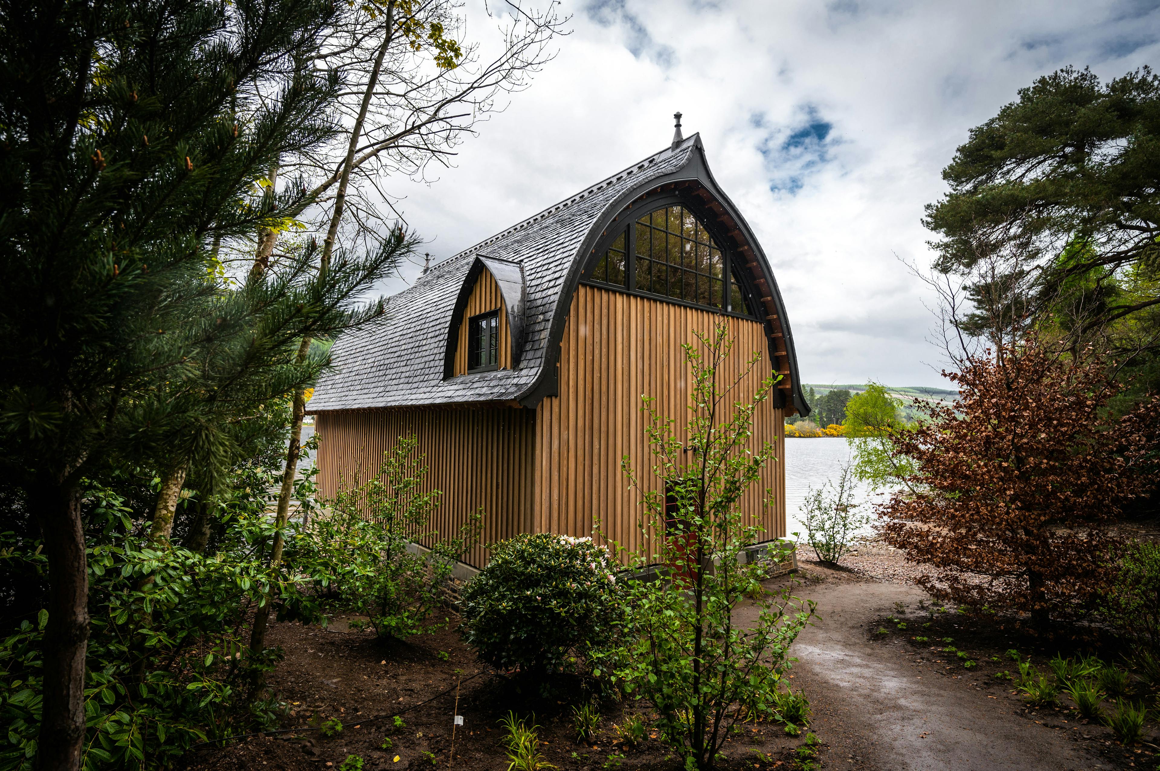 The back of a timber framed boathouse on loch ness with a curved roof