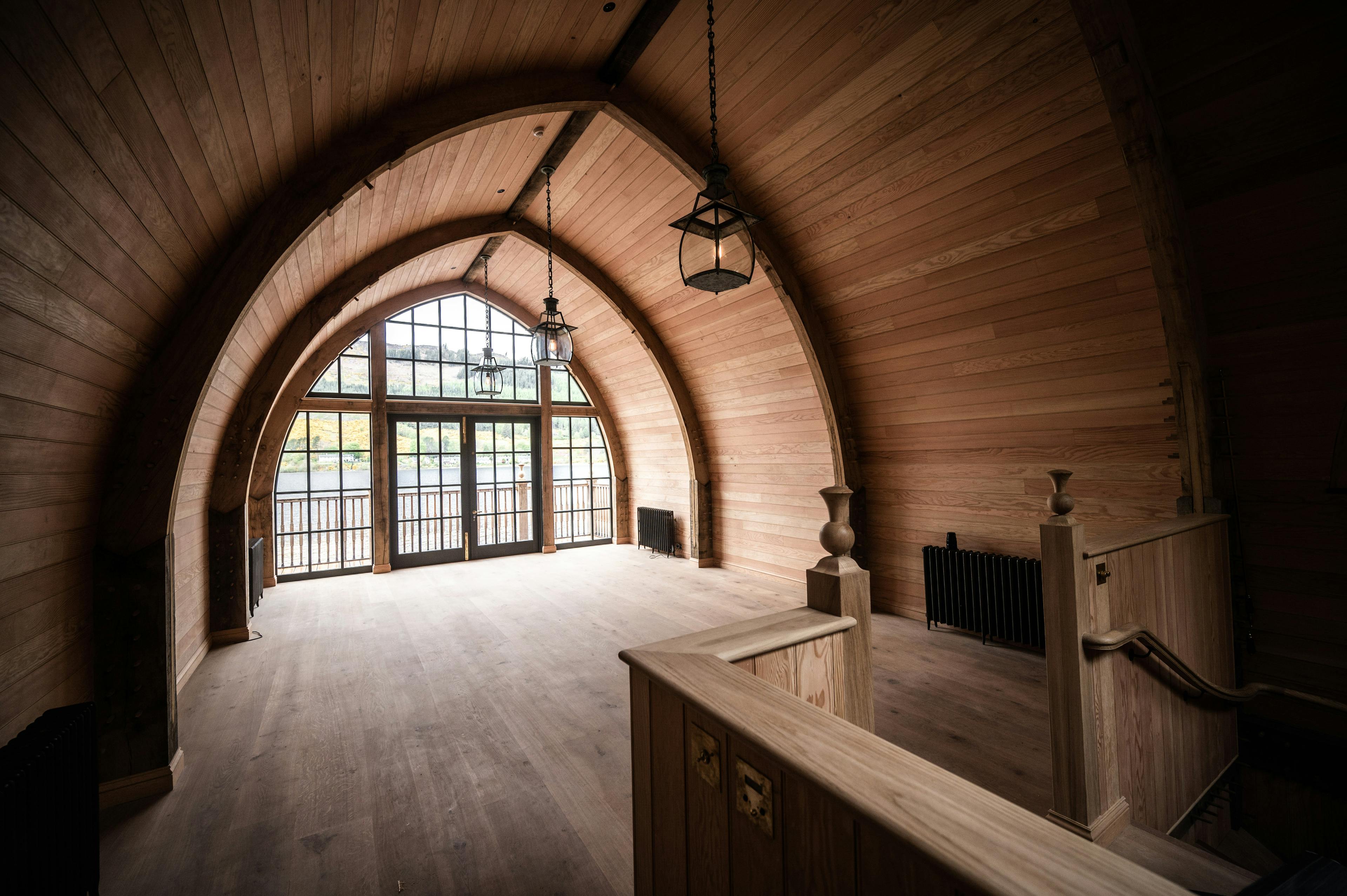 The inside of a timber framed boathouse with a glazed gable end and a curved roof on loch ness