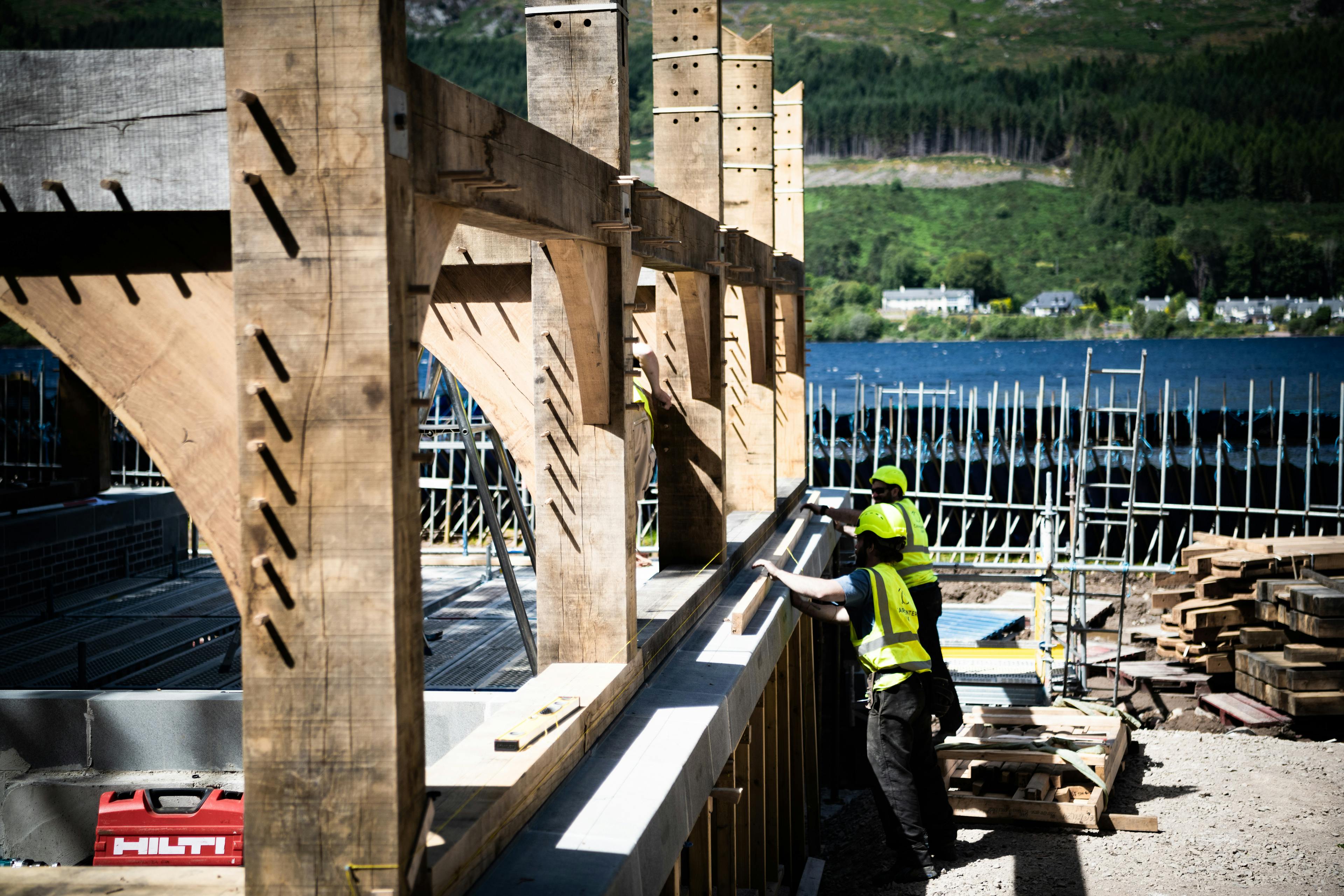 Carpenters install an oak framed boathouse by a lake