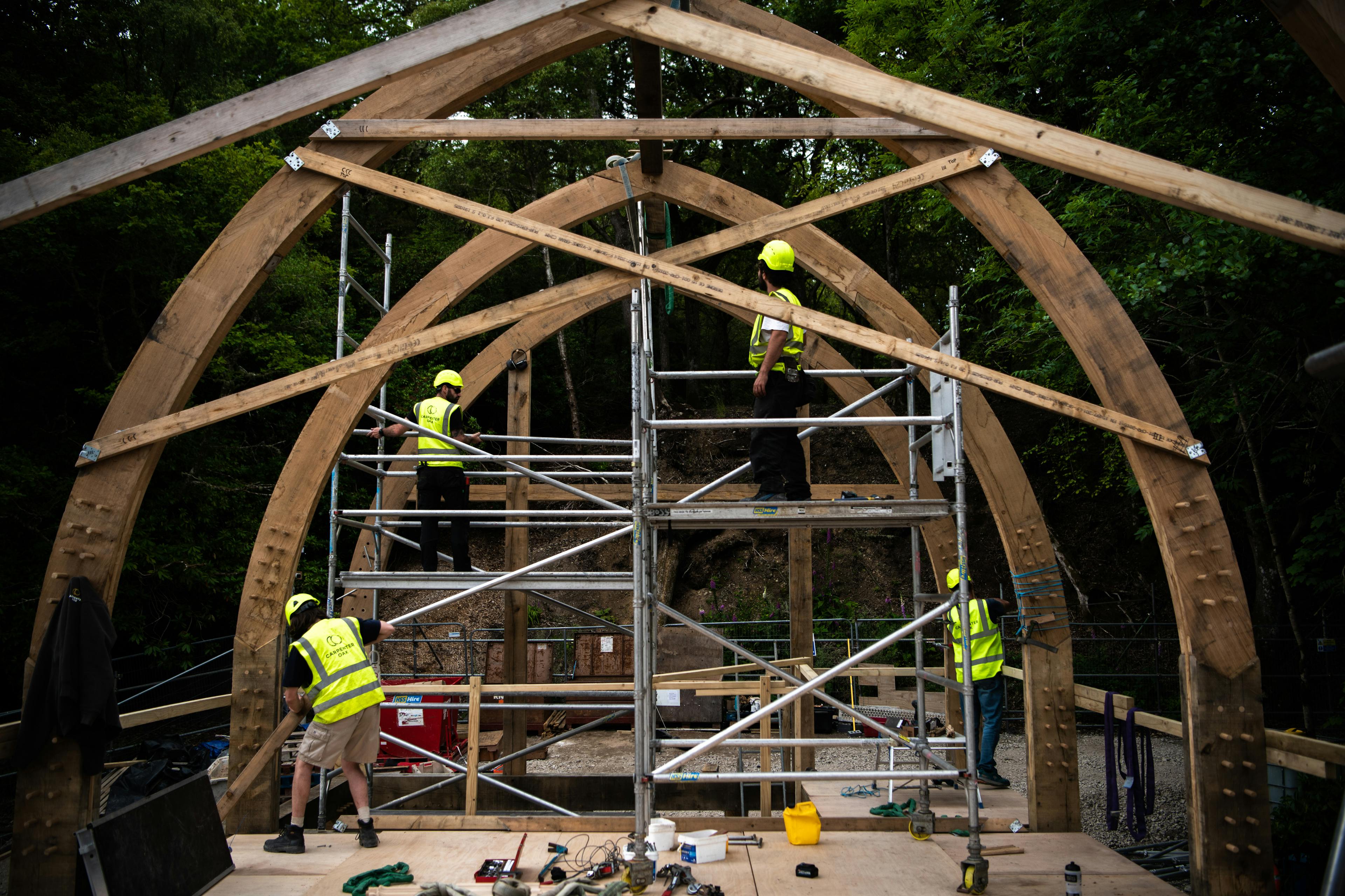 Carpenters install an oak framed boathouse with a curved roof