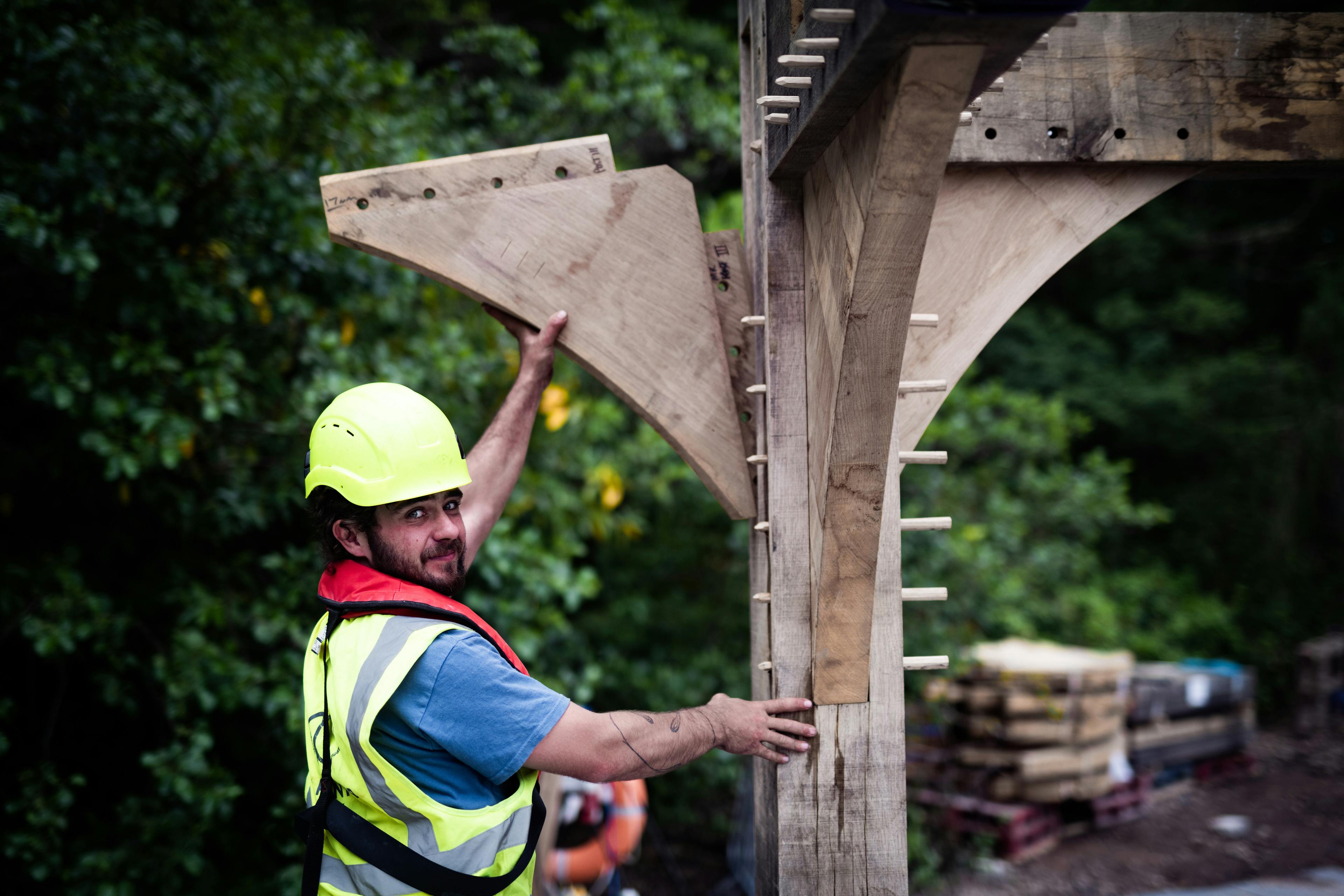 A carpenter installs an oak framed boathouse by a lake