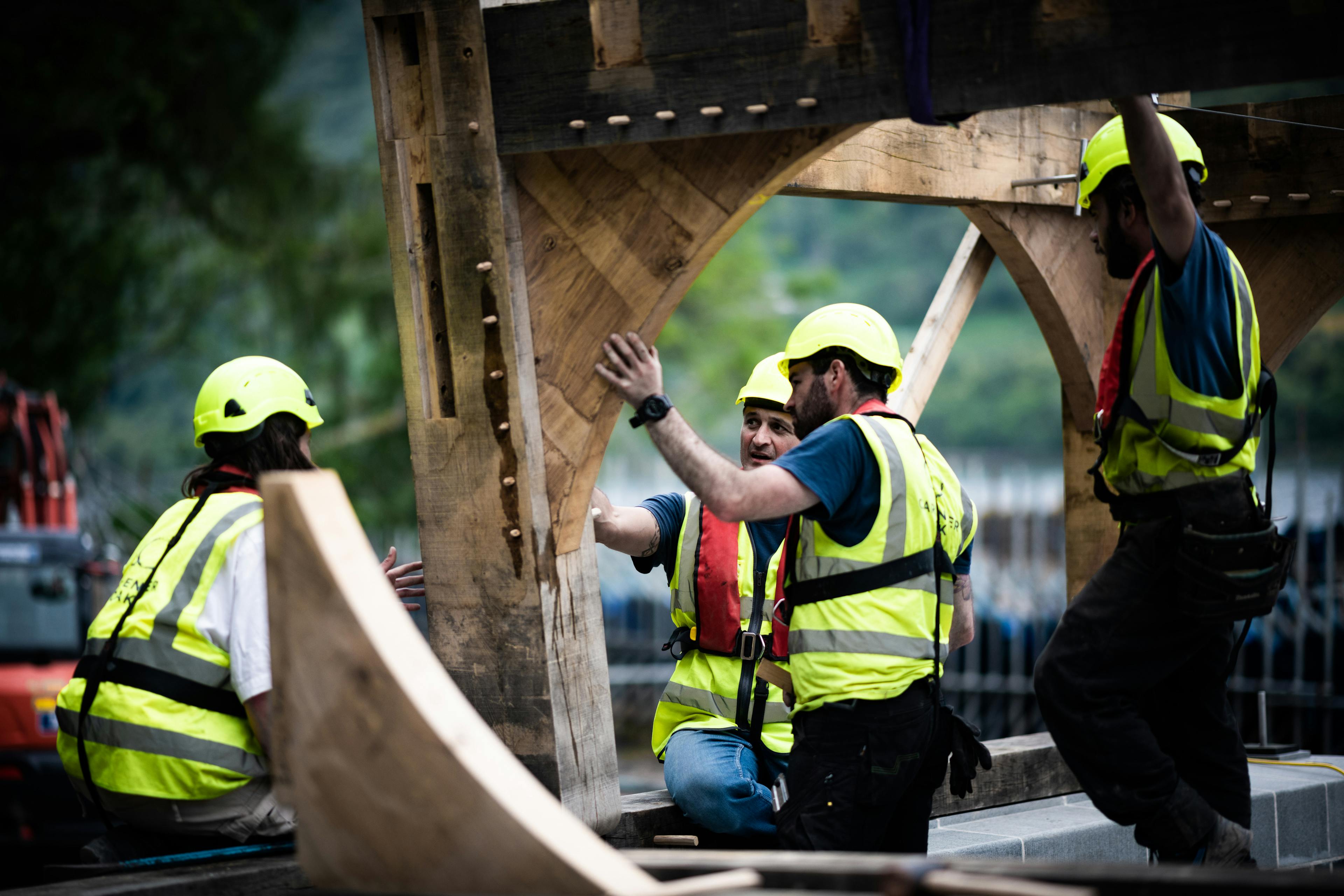 Carpenters installing the oak frame of a timber boathouse on loch ness with a curved roof during construction