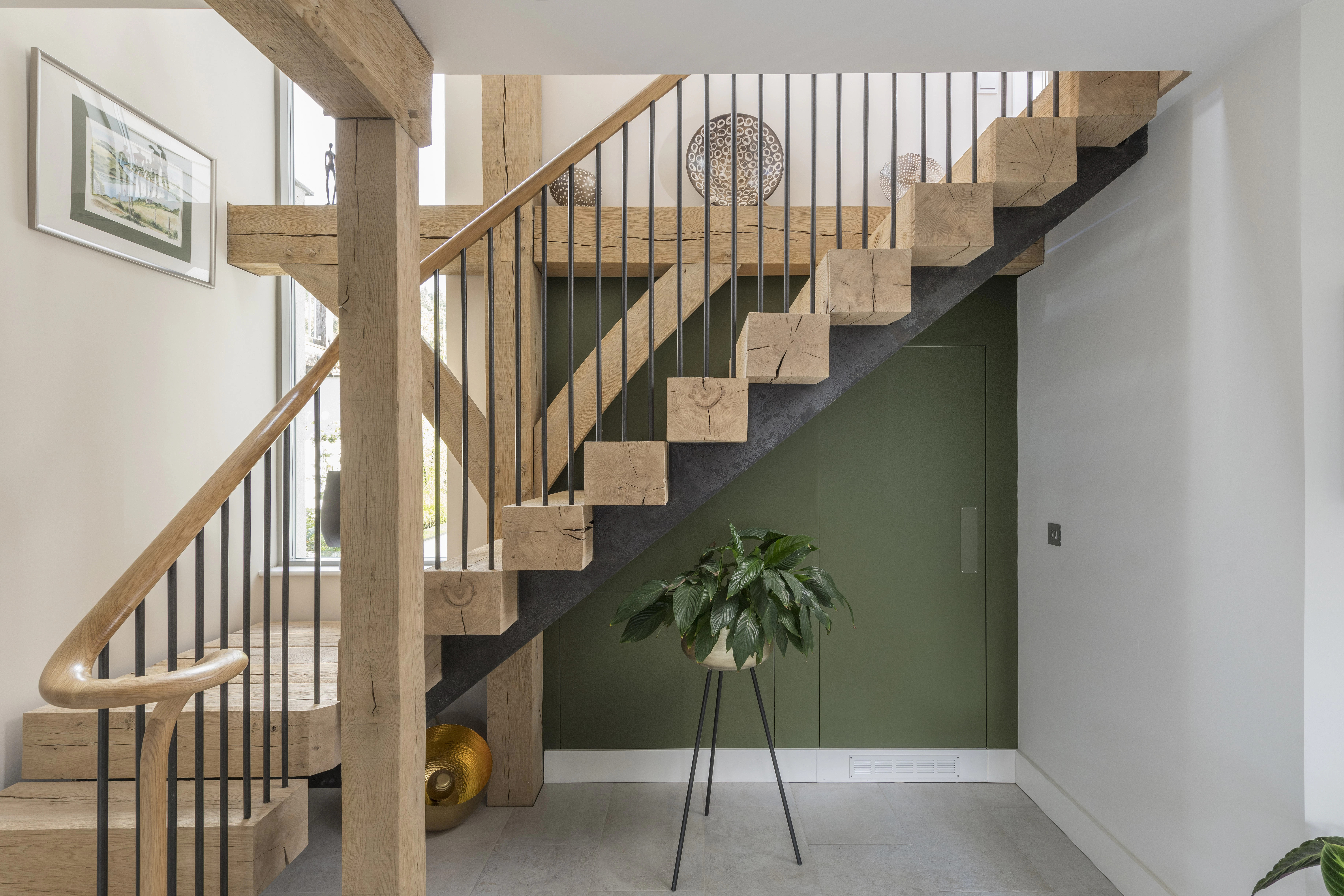 Wooden L shaped stairs nestled into an oak frame with a green painted wall behind