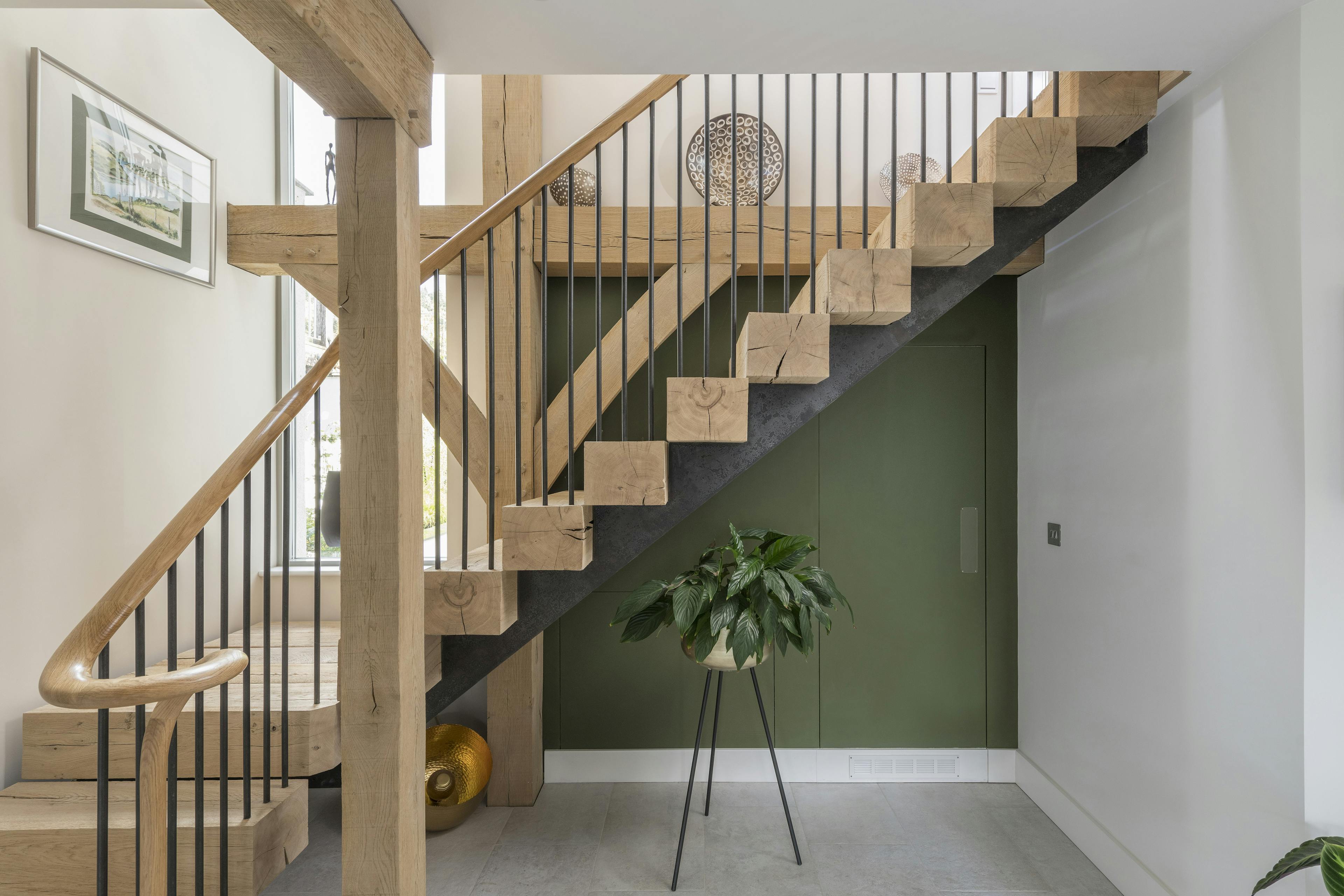 Wooden L shaped stairs nestled into an oak frame with a green painted wall behind