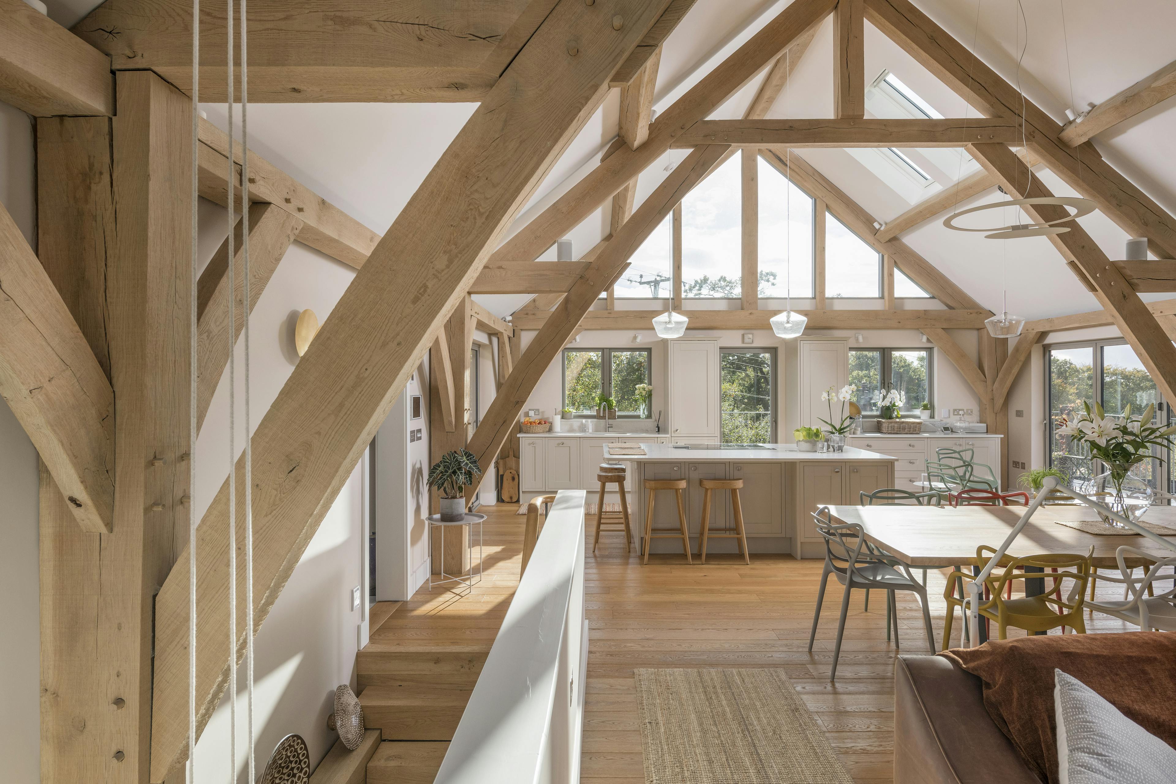 A stairwell leads to a dining area and kitchen in a vaulted oak framed open plan living room